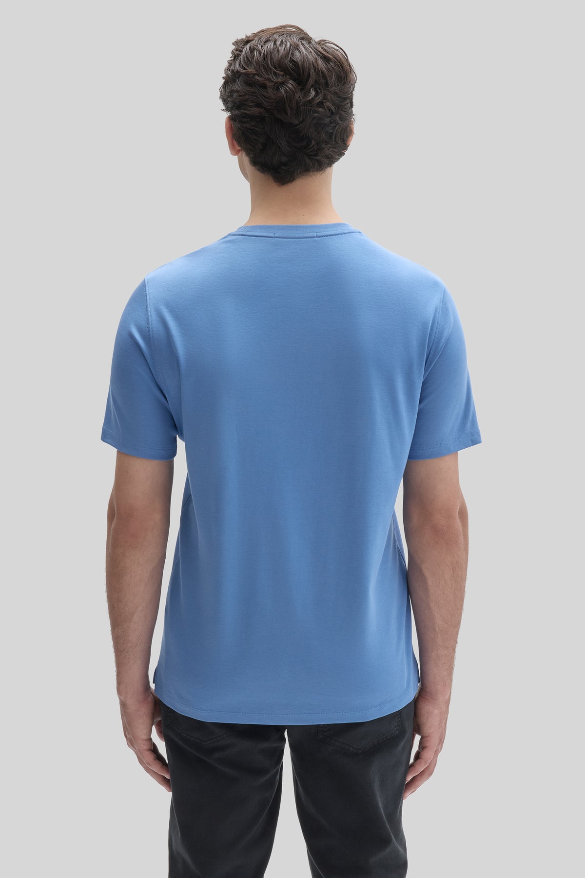 Man wearing a blue short-sleeve crew neck t-shirt, shown from back view.