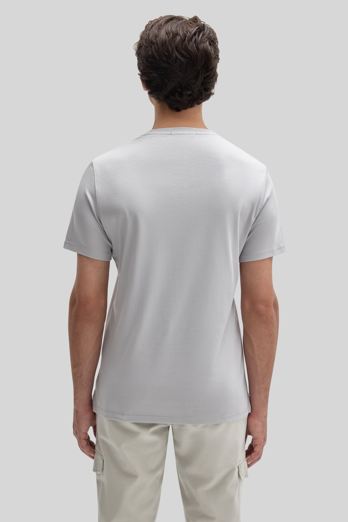 Man wearing light gray short-sleeve crew neck t-shirt with cream cargo pants, shown from back view.