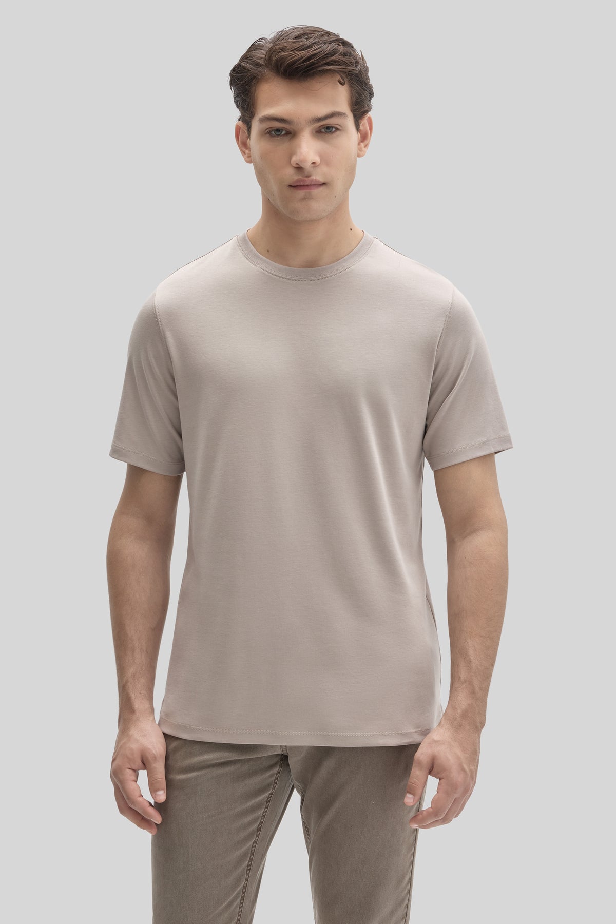 Man wearing a beige crewneck short-sleeve tee with khaki pants.