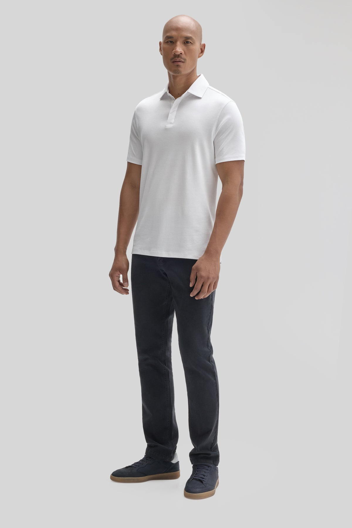 Man wearing white short-sleeve polo shirt with covered placket and dark jeans.