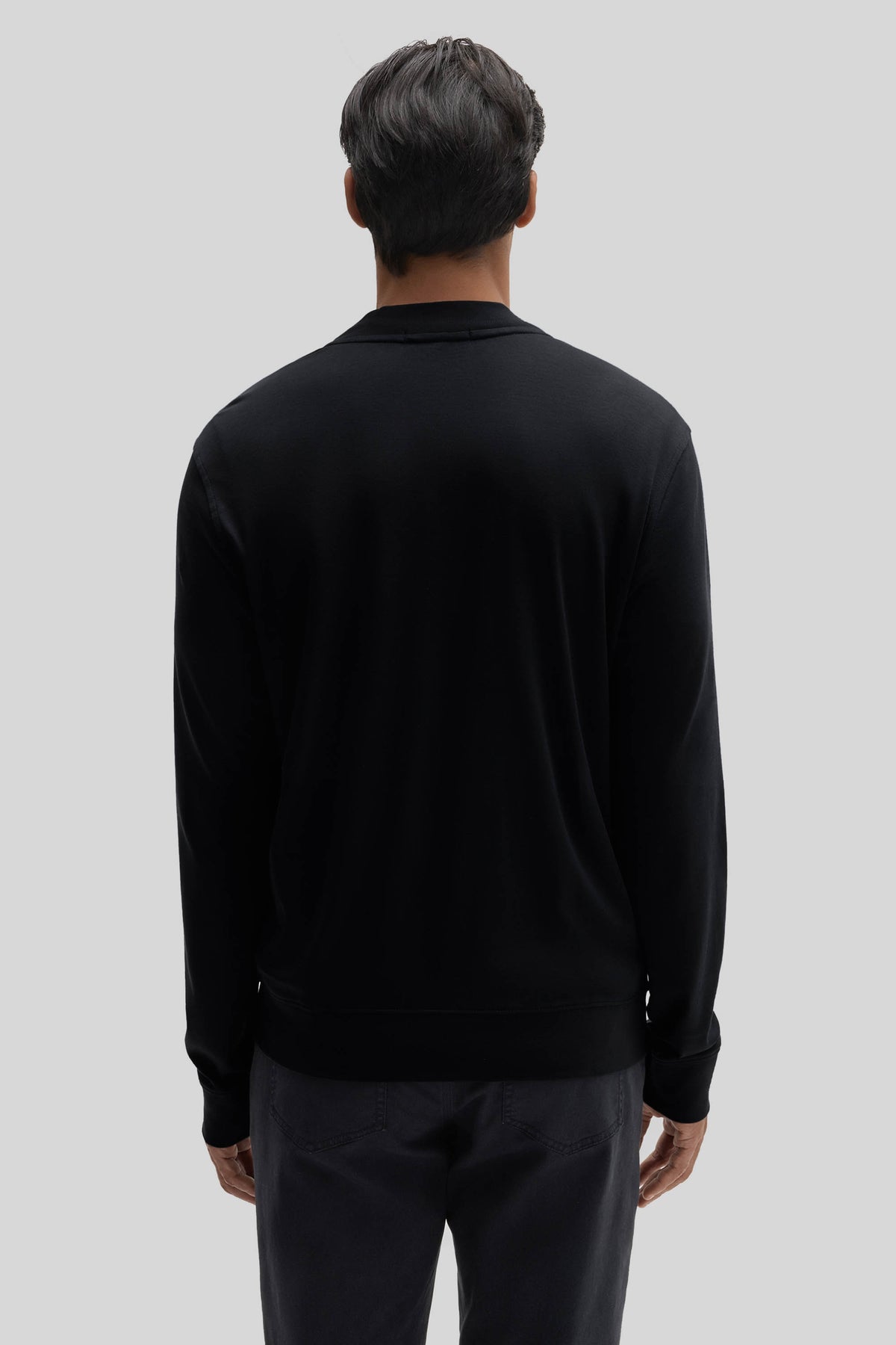 Black baseball jacket with collar and ribbed cuffs, shown from back view on model wearing dark pants.