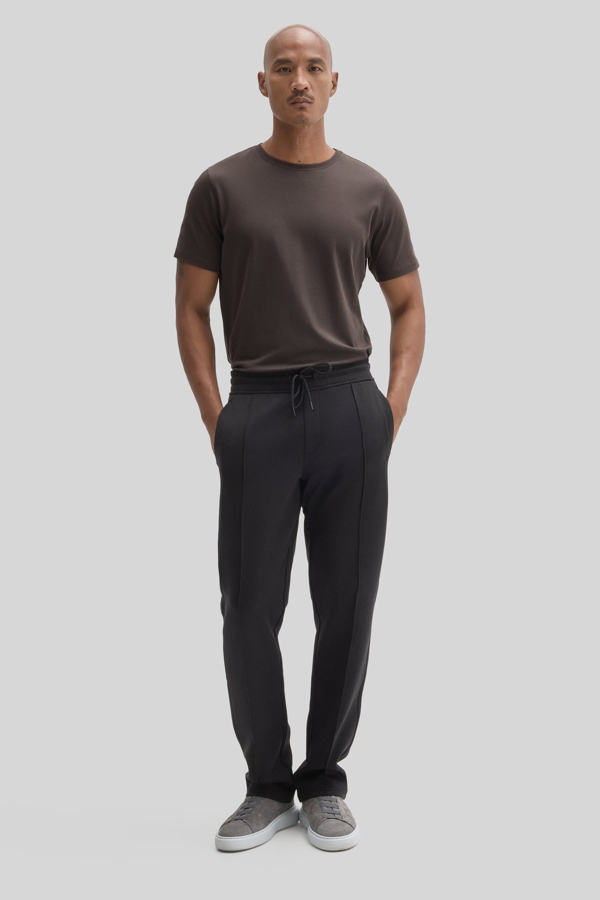 Man wearing black jogging pants with drawstring waist and side seams, paired with a gray t-shirt.