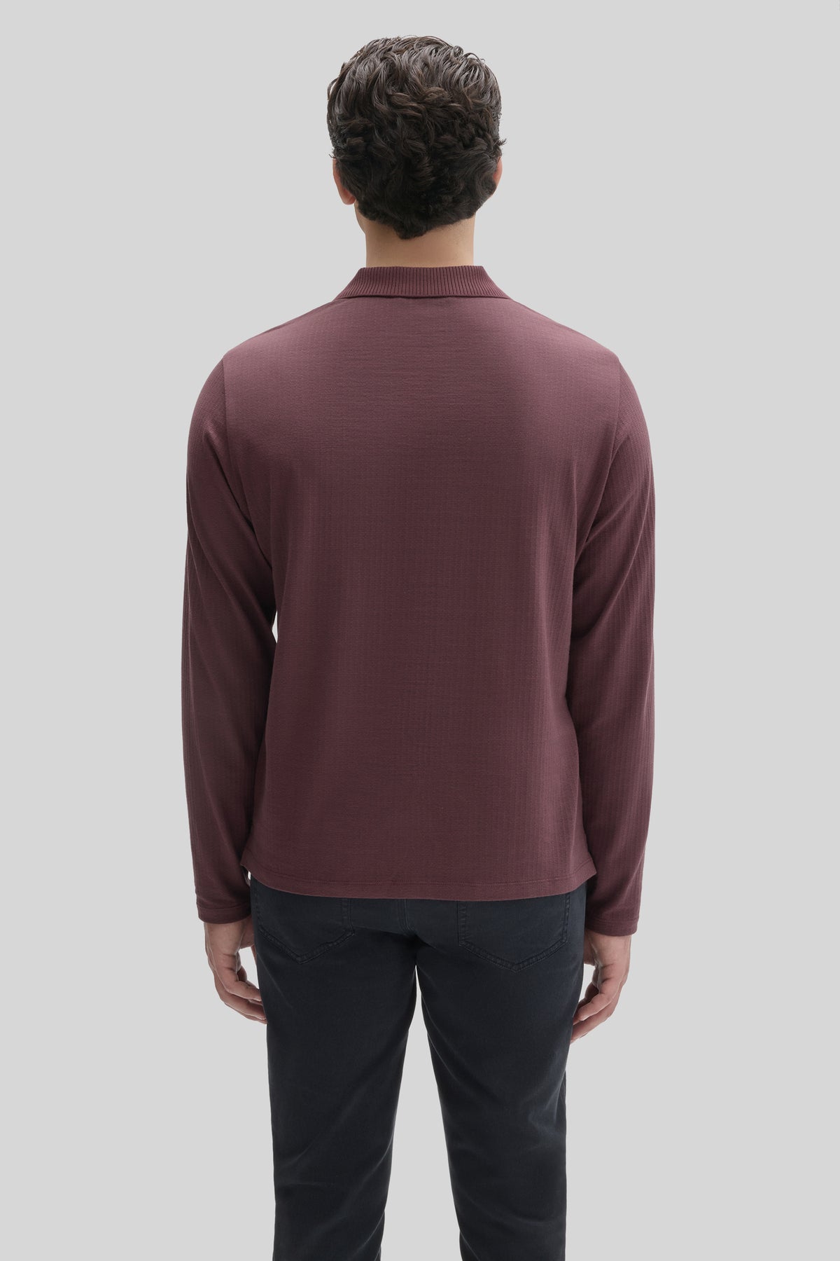 Burgundy long sleeve polo with ribbed collar and placket zip, worn with dark navy pants, shown from back view.