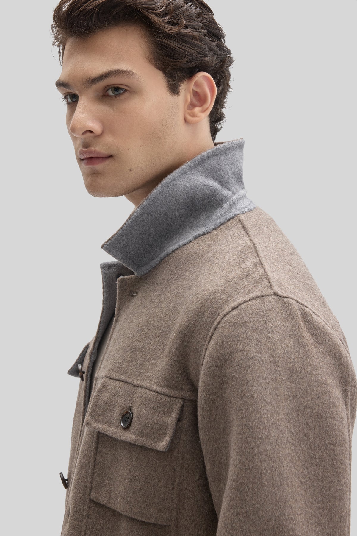 Beige wool jacket with gray collar, button front closure, and chest pockets on model shown in profile.