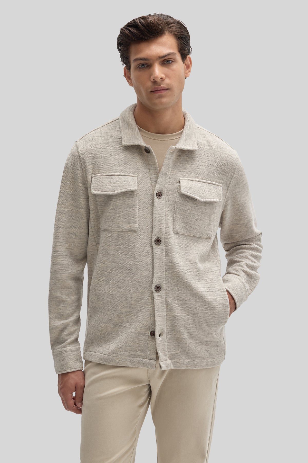 Beige overshirt with collar, button front, and two chest pockets worn over a cream base layer.