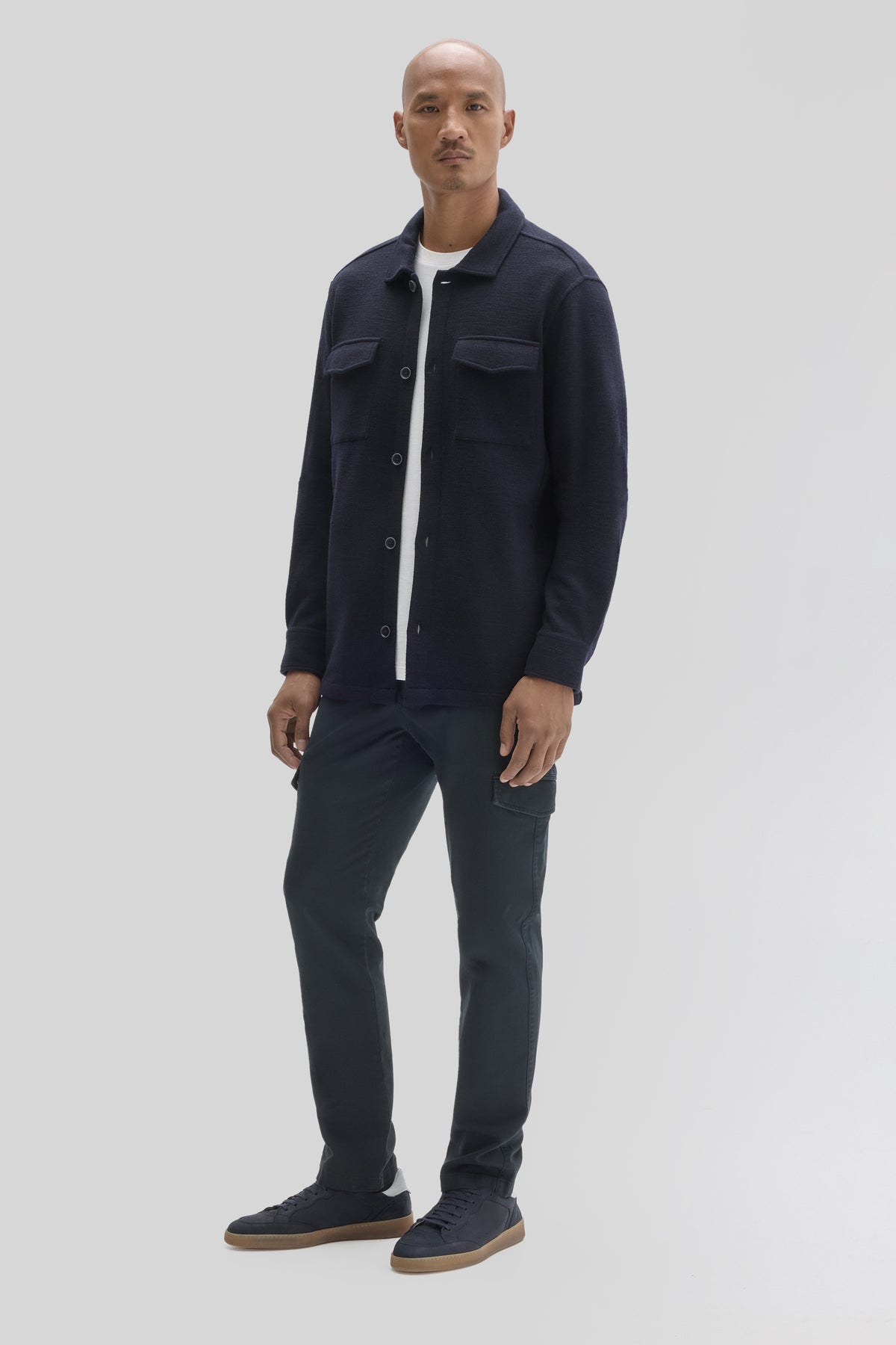 Navy button-front overshirt with chest pockets worn over white shirt, styled with dark jeans.