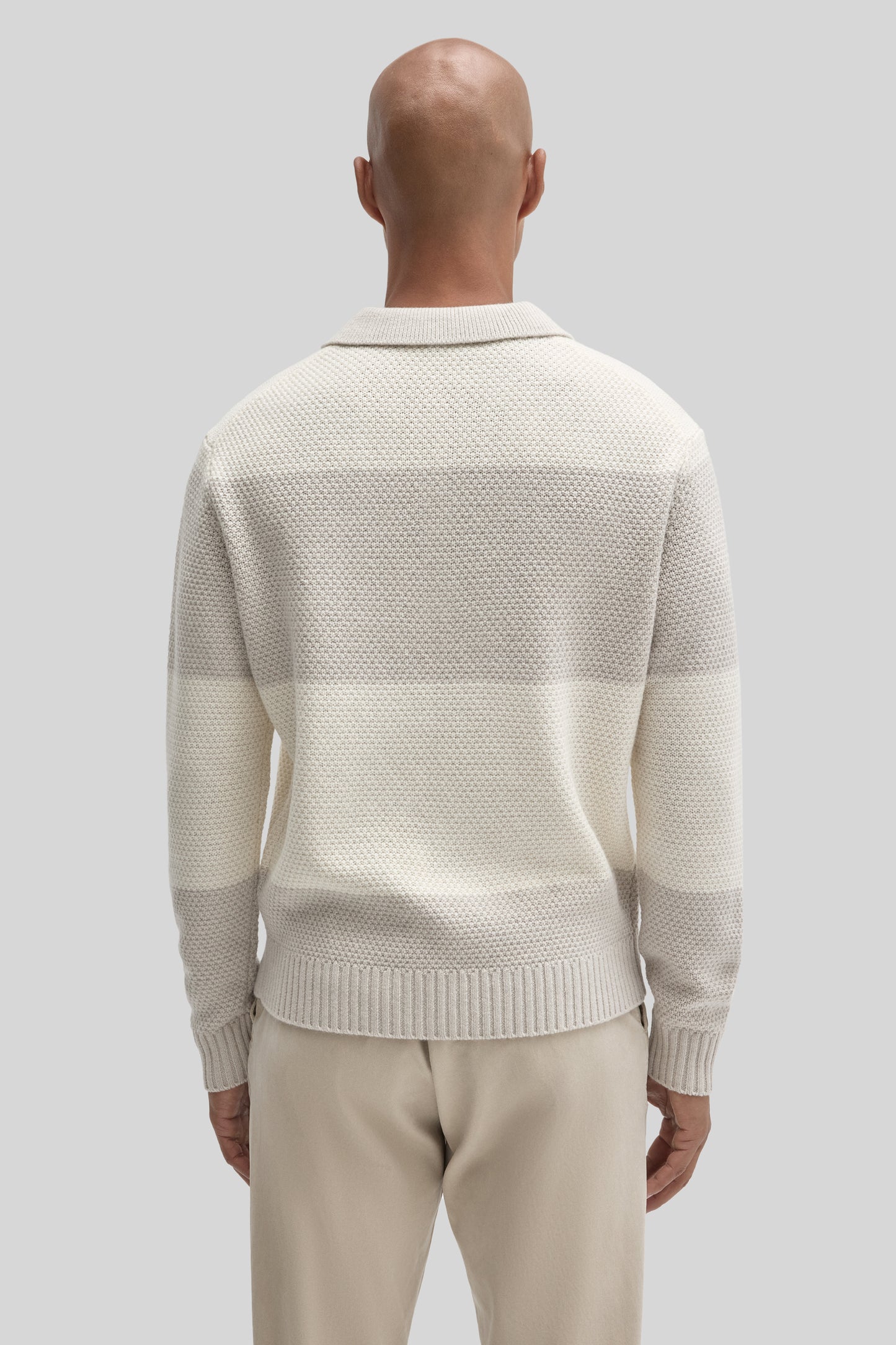 Cream-colored rugby polo sweater with textured knit fabric and ribbed collar, worn with beige pants.