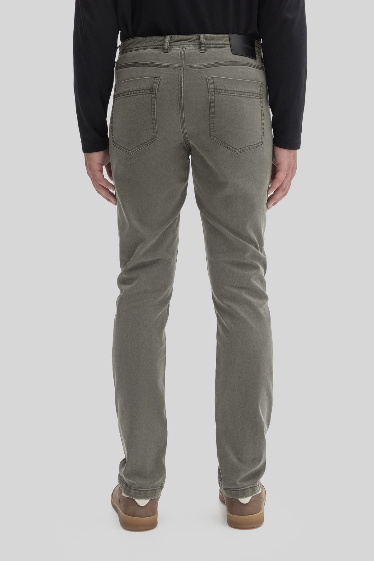 Sage green five-pocket pants with visible back pockets and stitching details, shown from behind on a model wearing a black lo