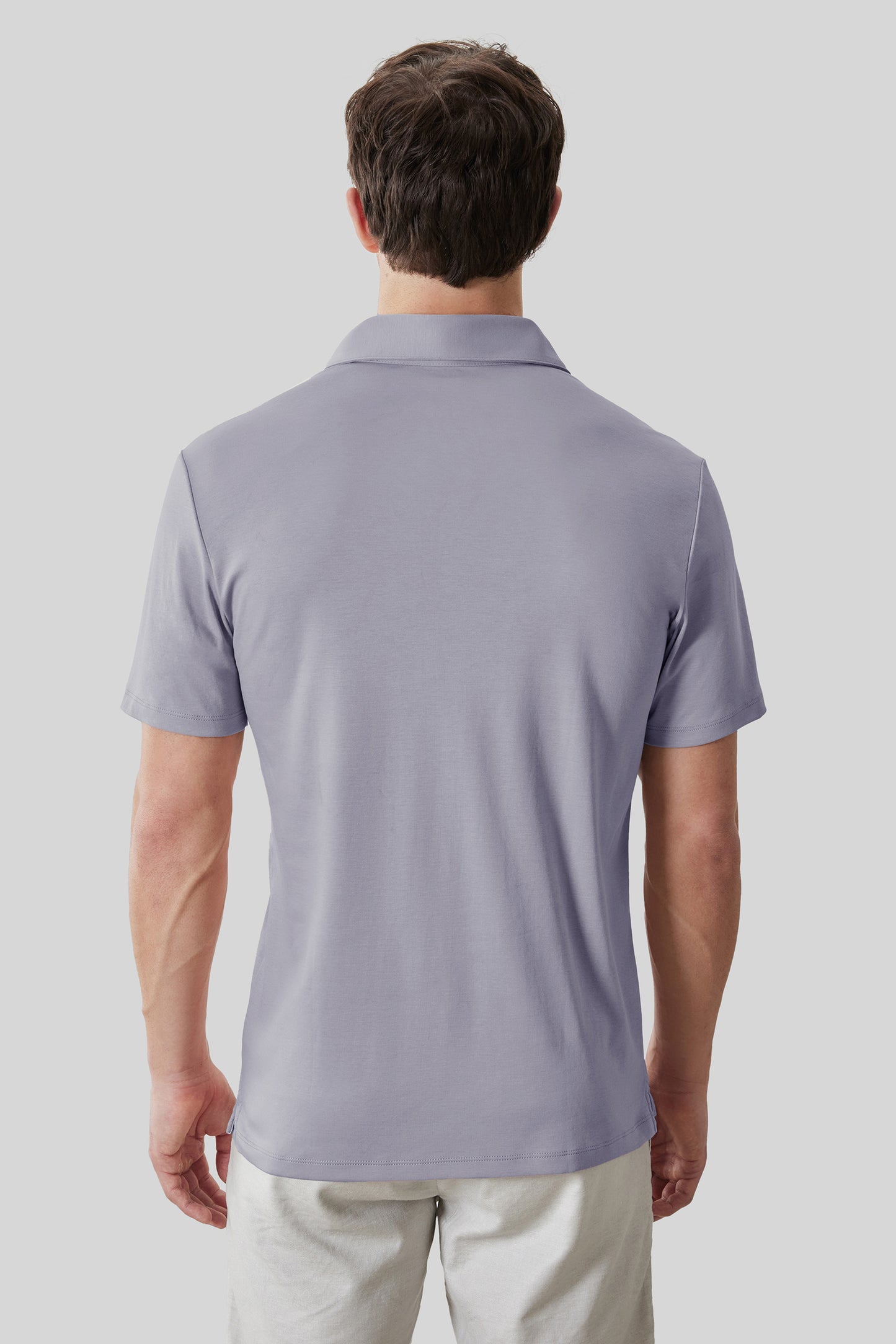 Man wearing lavender short-sleeve polo shirt with collar, shown from back view.