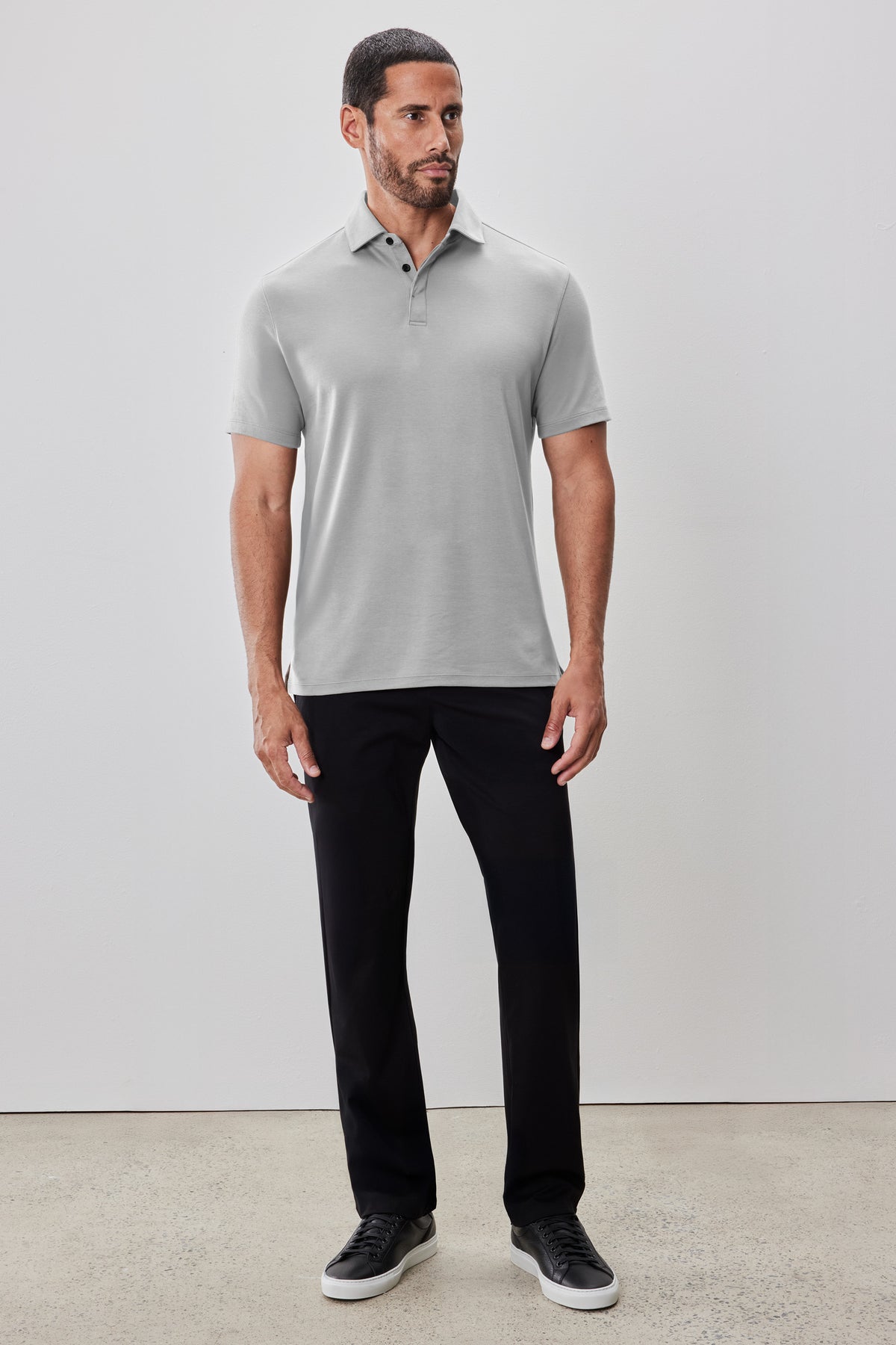 Light gray short-sleeve polo shirt with covered placket worn with black pants.