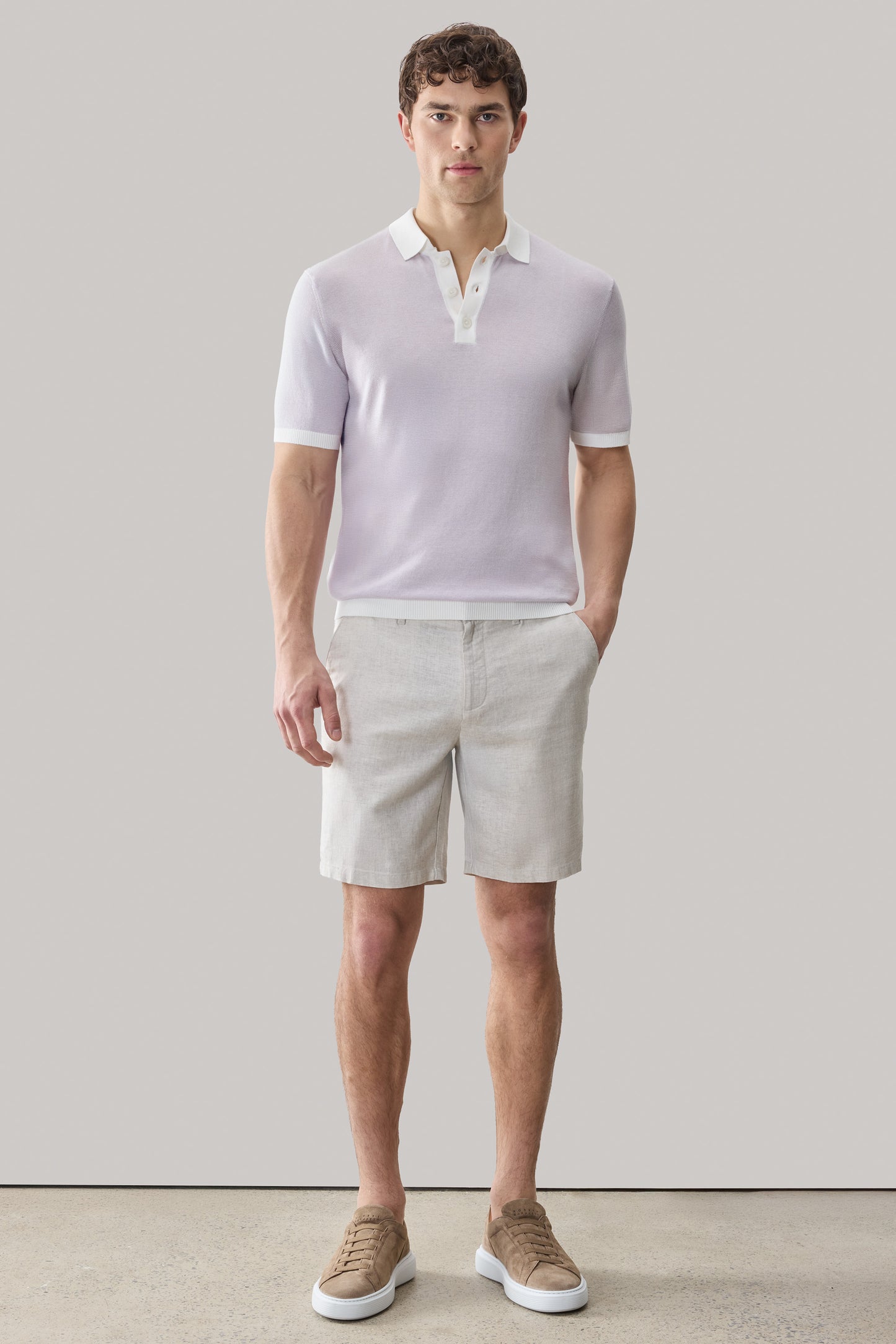 Man wearing lavender short-sleeve polo sweater with white collar and beige shorts.