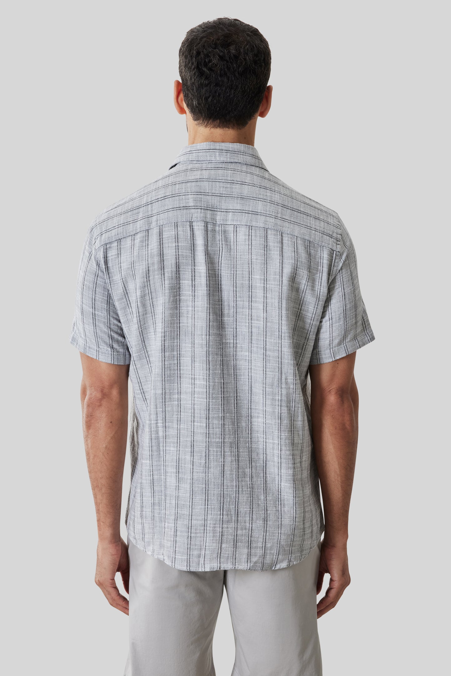 Light gray short sleeve button-up shirt with vertical stripe pattern, shown from back view on model.