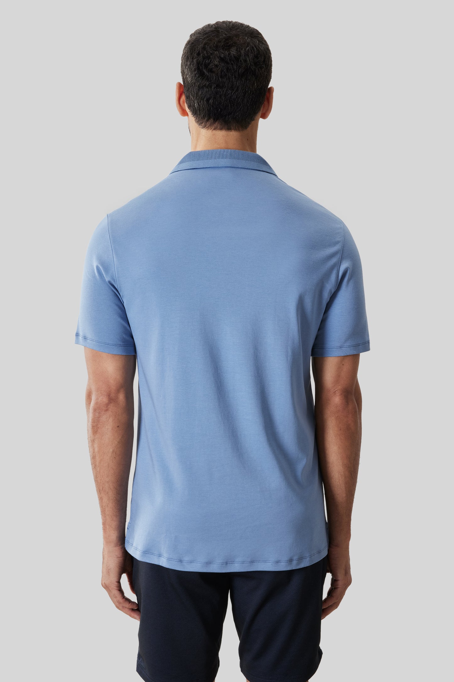 Light blue short-sleeve polo shirt with textured collar, shown on male model from back view.