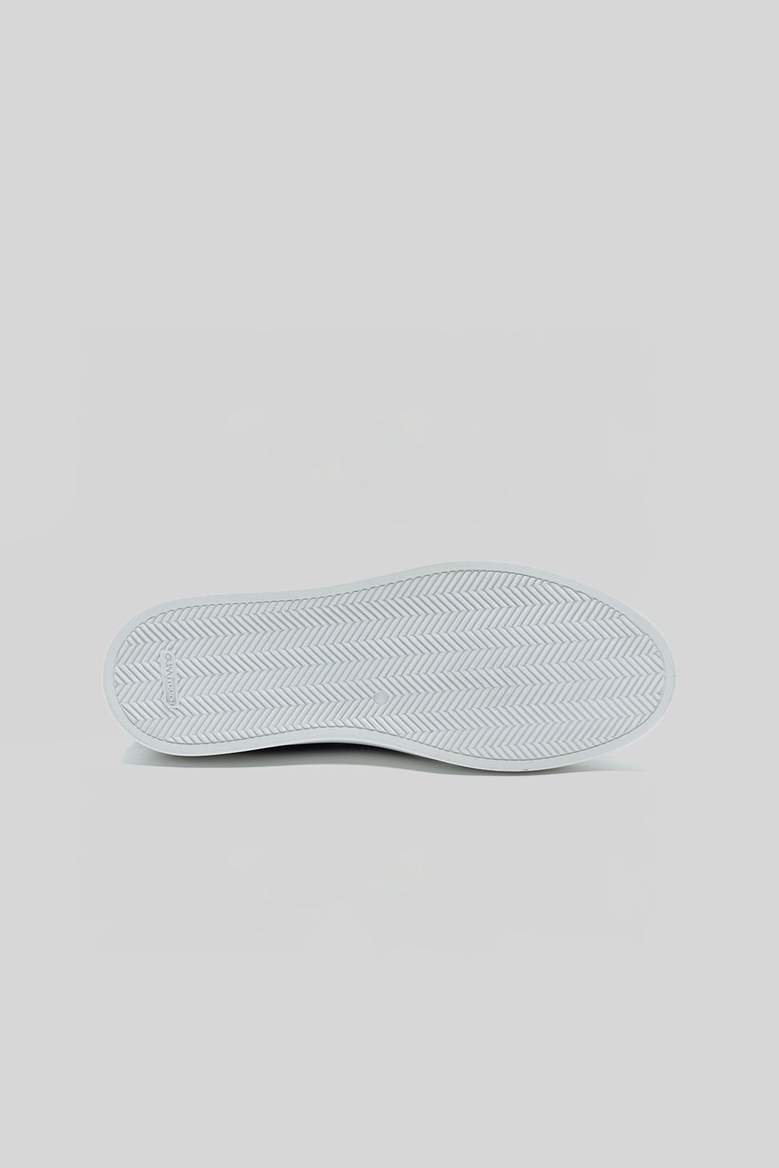White sneaker sole with herringbone tread pattern, shown from bottom view.