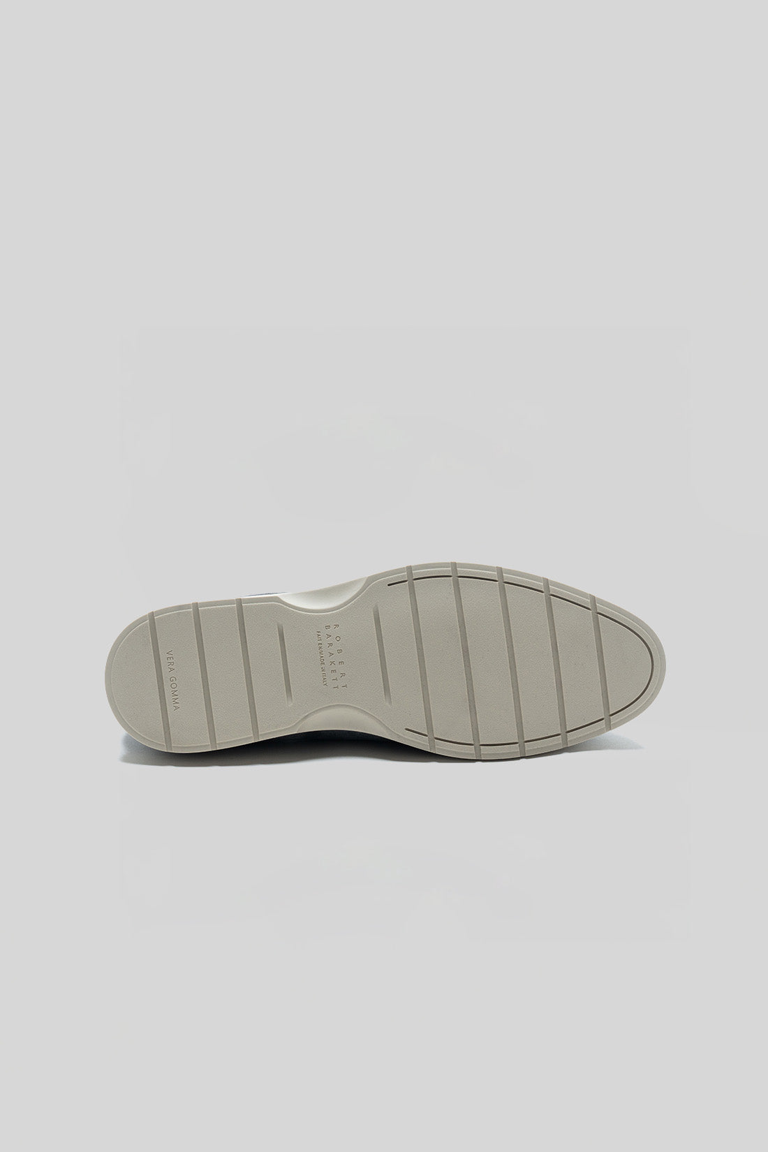 Beige rubber sole of a loafer shoe with grooved tread pattern and curved design.