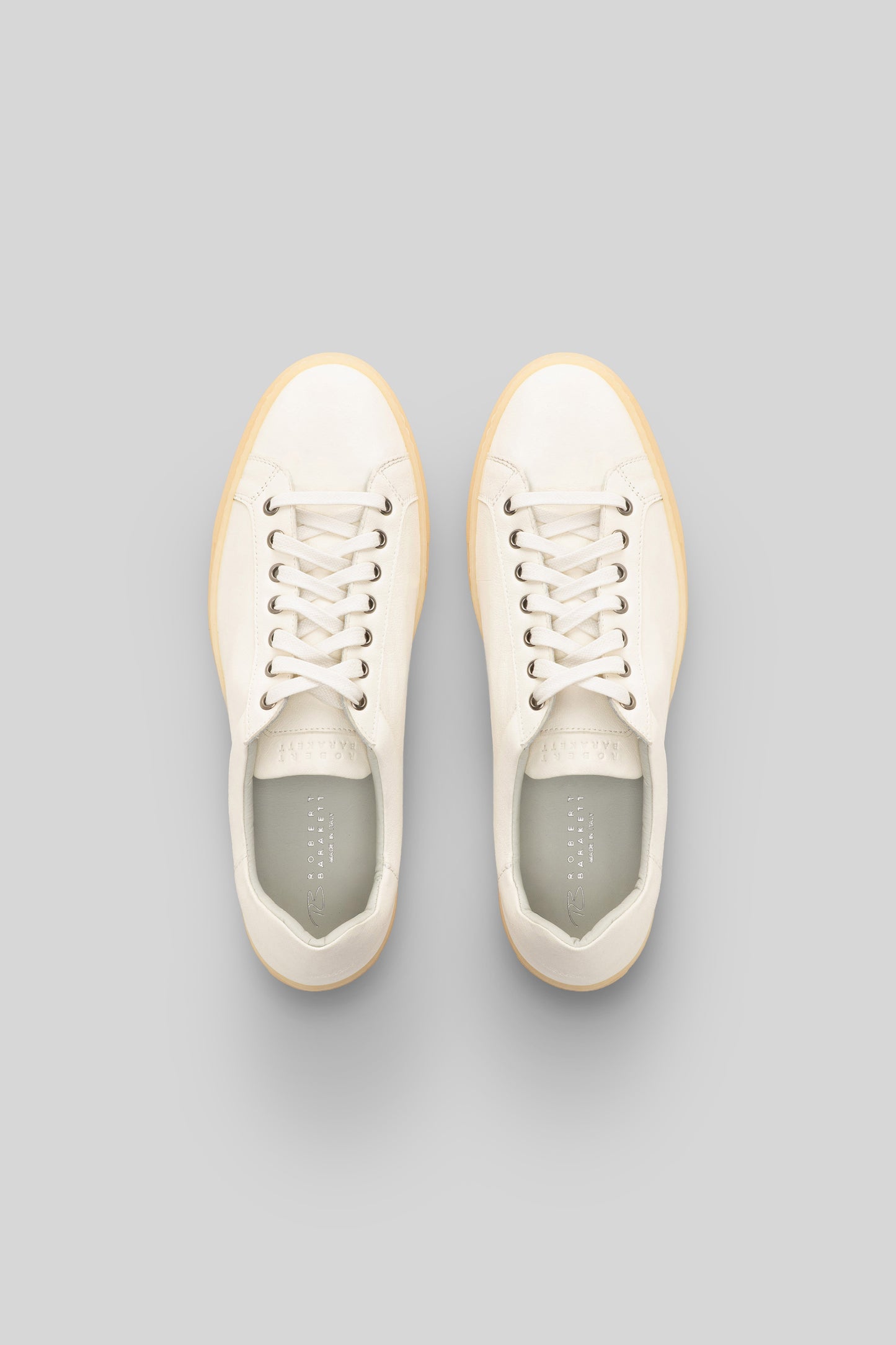 Cream leather sneakers with cream laces, tan rubber sole, and gray insoles shown from above.
