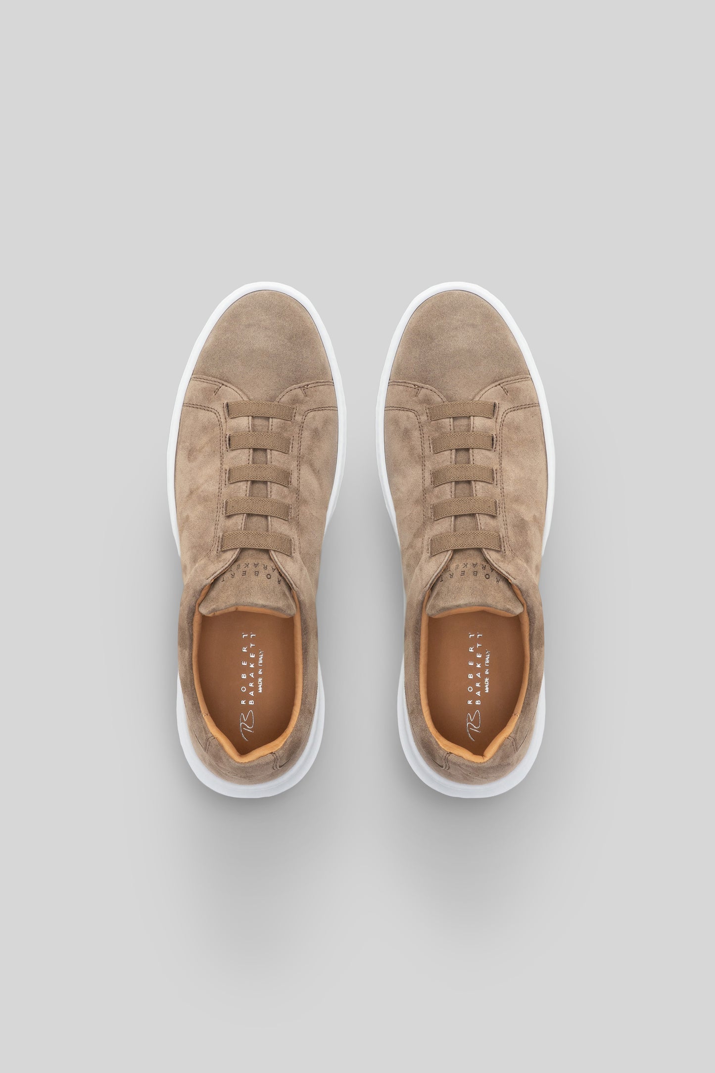 Beige suede sneakers with white sole and tan laces, shown from above.