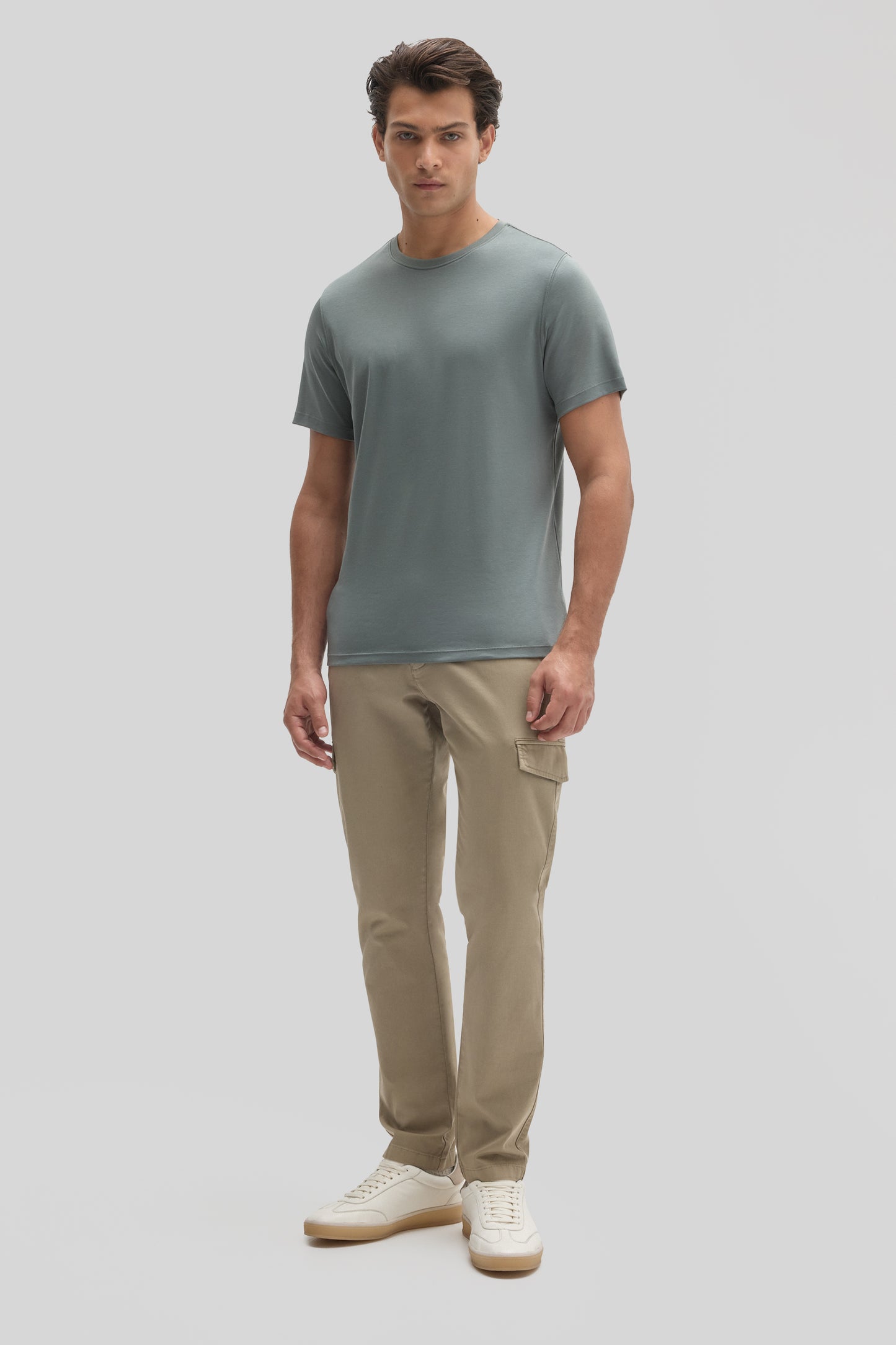 Man wearing gray crew-neck short-sleeve t-shirt and beige cargo pants with white sneakers.