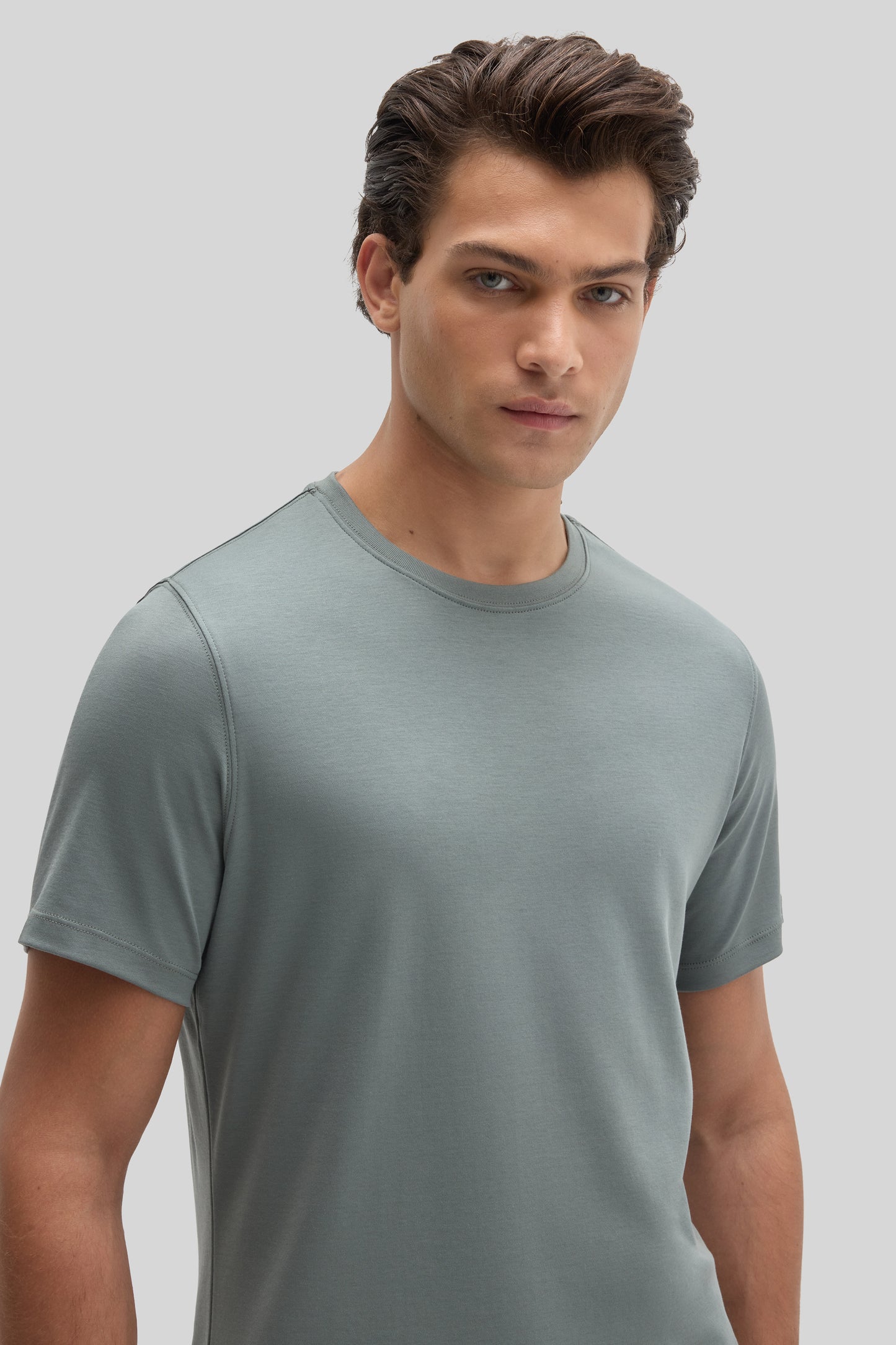 Man wearing a sage green short-sleeve crew neck t-shirt against a neutral background.