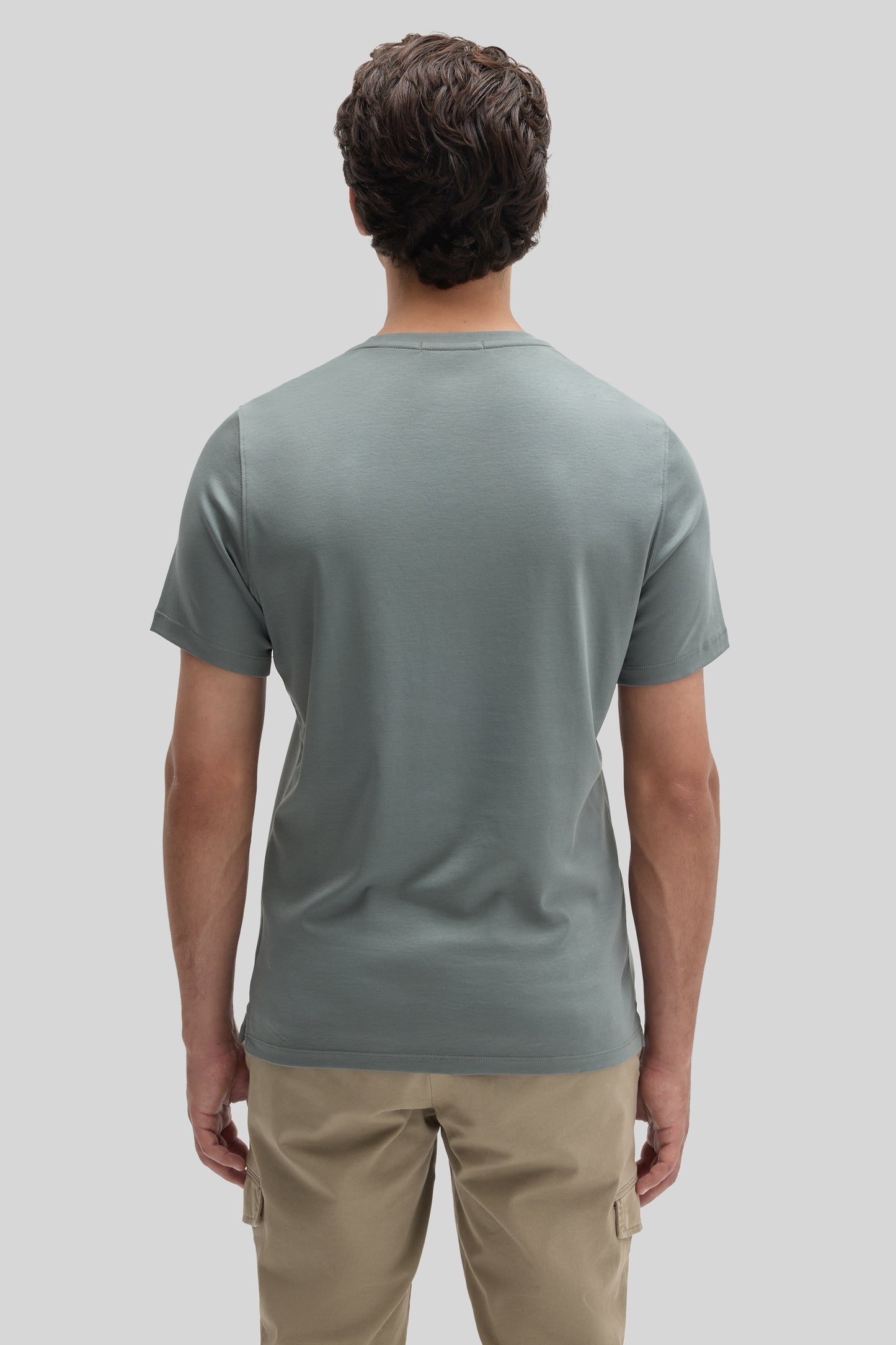 Man wearing sage green short-sleeve t-shirt and beige cargo pants, shown from behind.