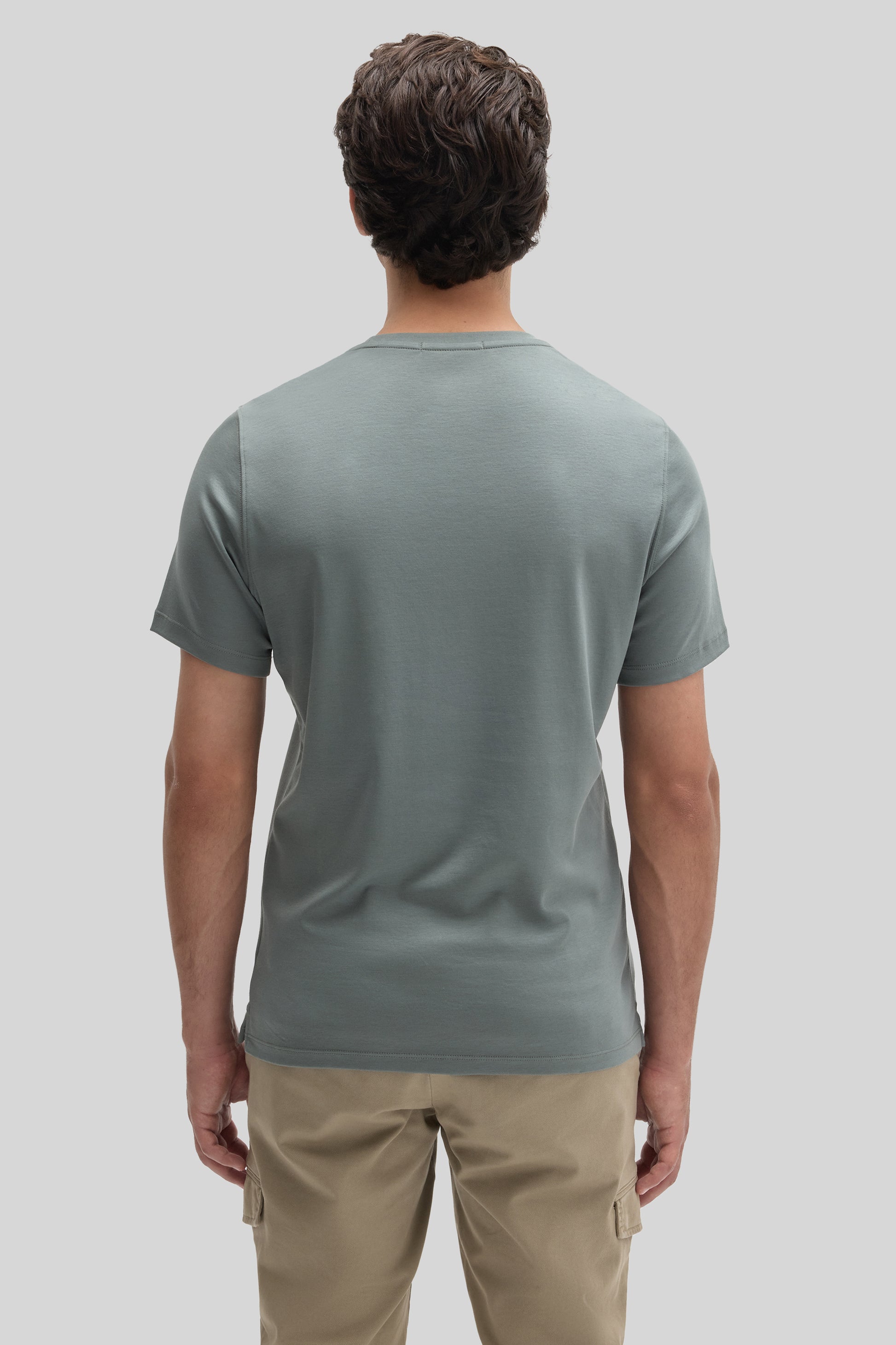 Man wearing sage green short-sleeve t-shirt and beige cargo pants, shown from behind.
