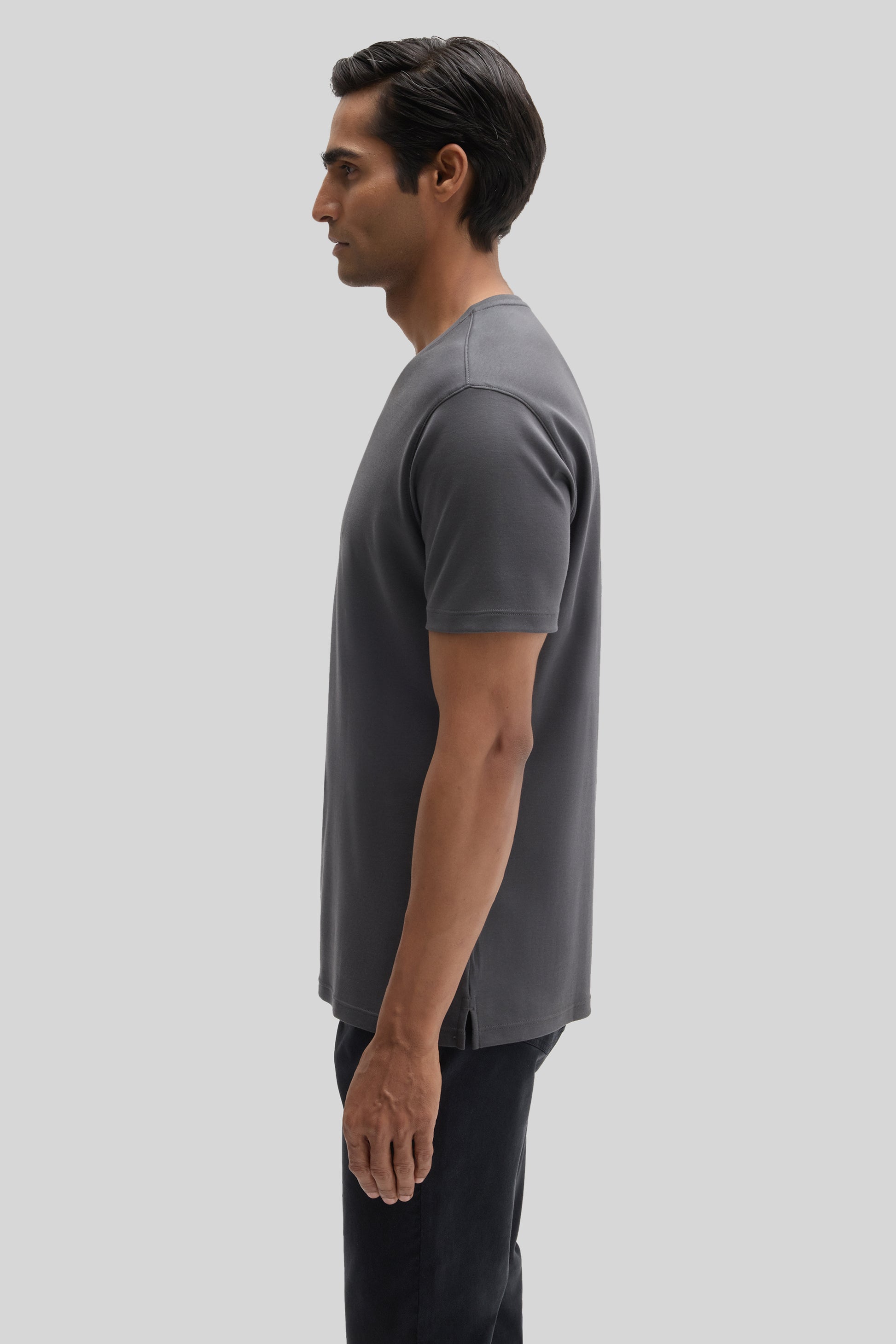 Man wearing gray V-neck short-sleeve t-shirt with black pants, shown in side profile.