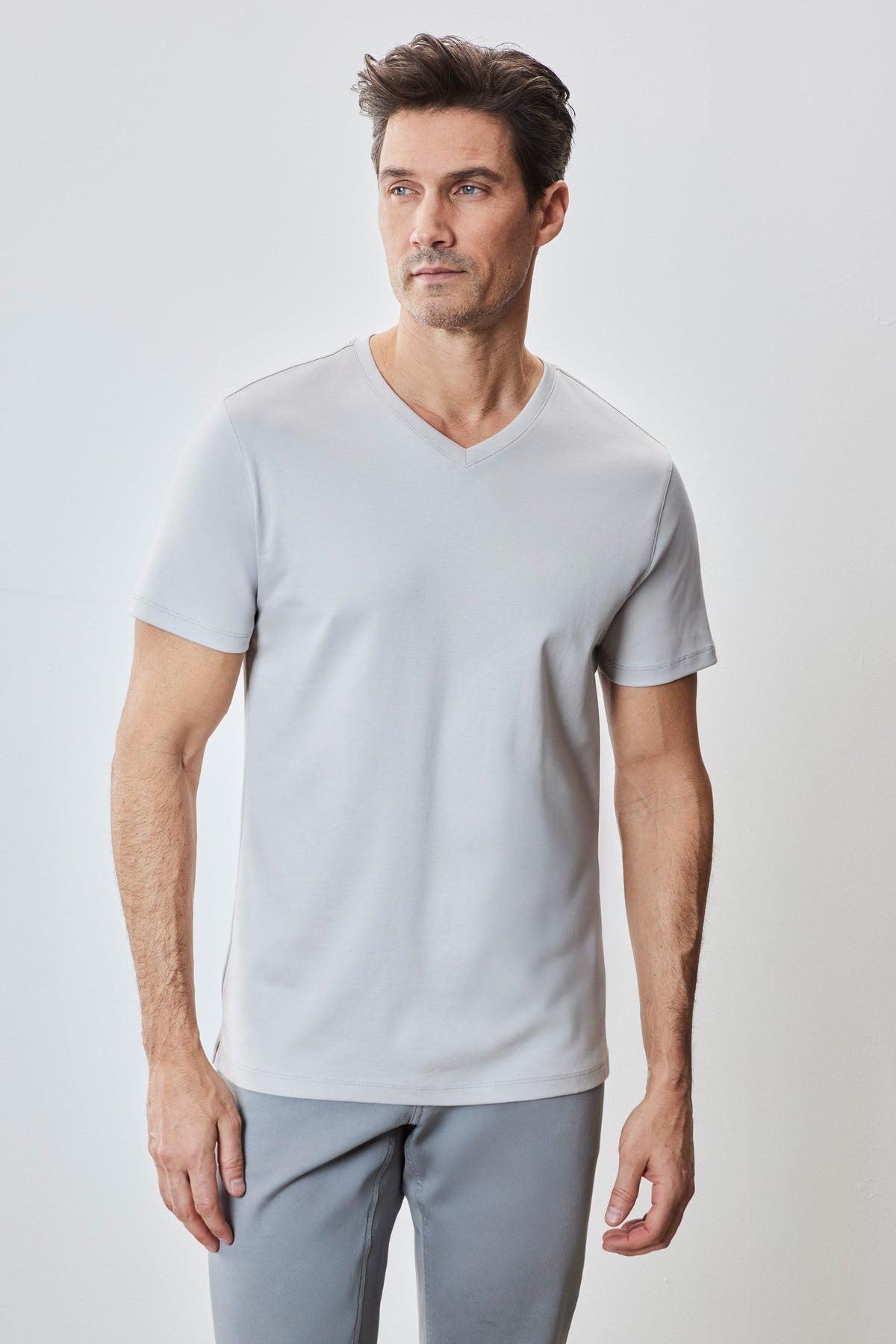 Man wearing light gray V-neck short-sleeve tee with gray pants.