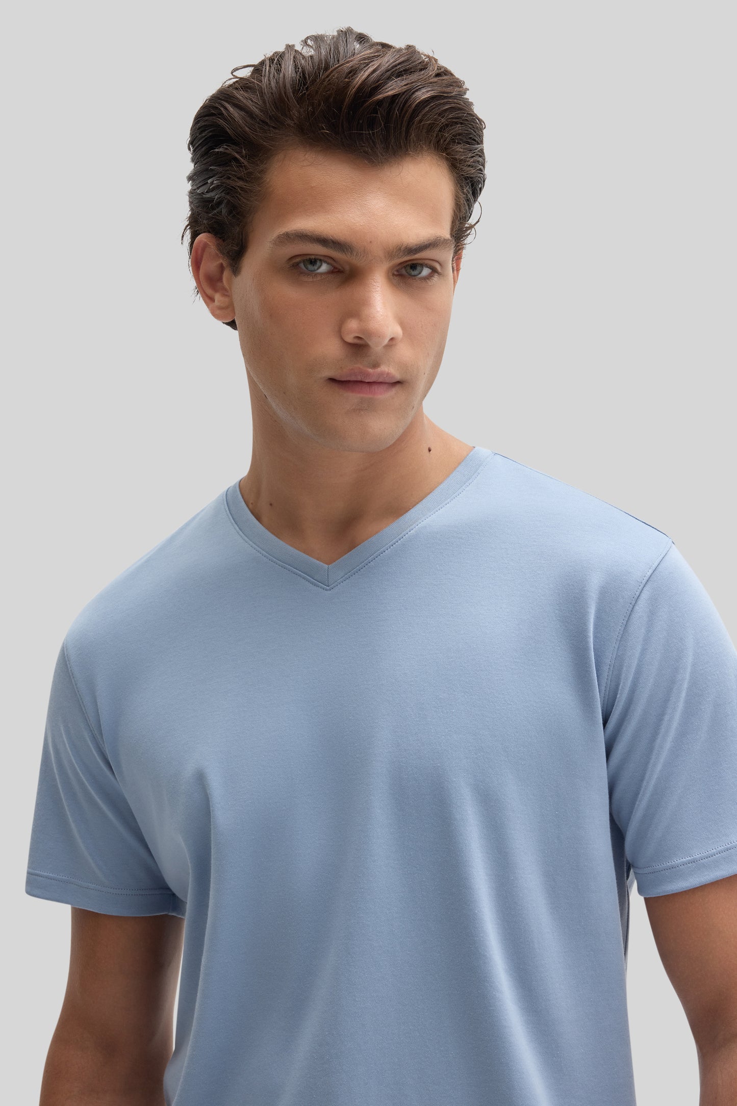 Man wearing light blue V-neck short-sleeve t-shirt against neutral background.