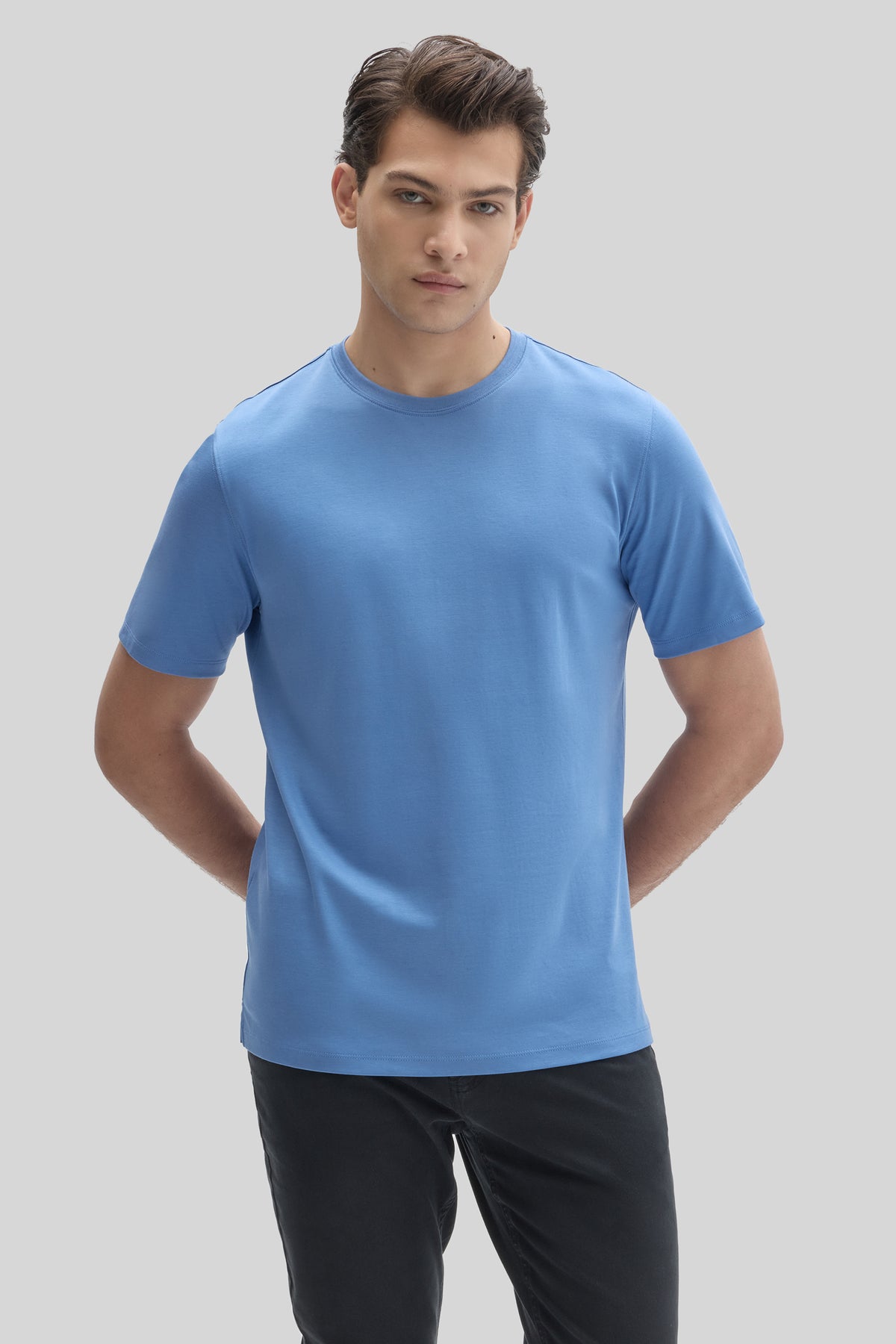 Man wearing a blue crew-neck t-shirt with short sleeves and black pants.