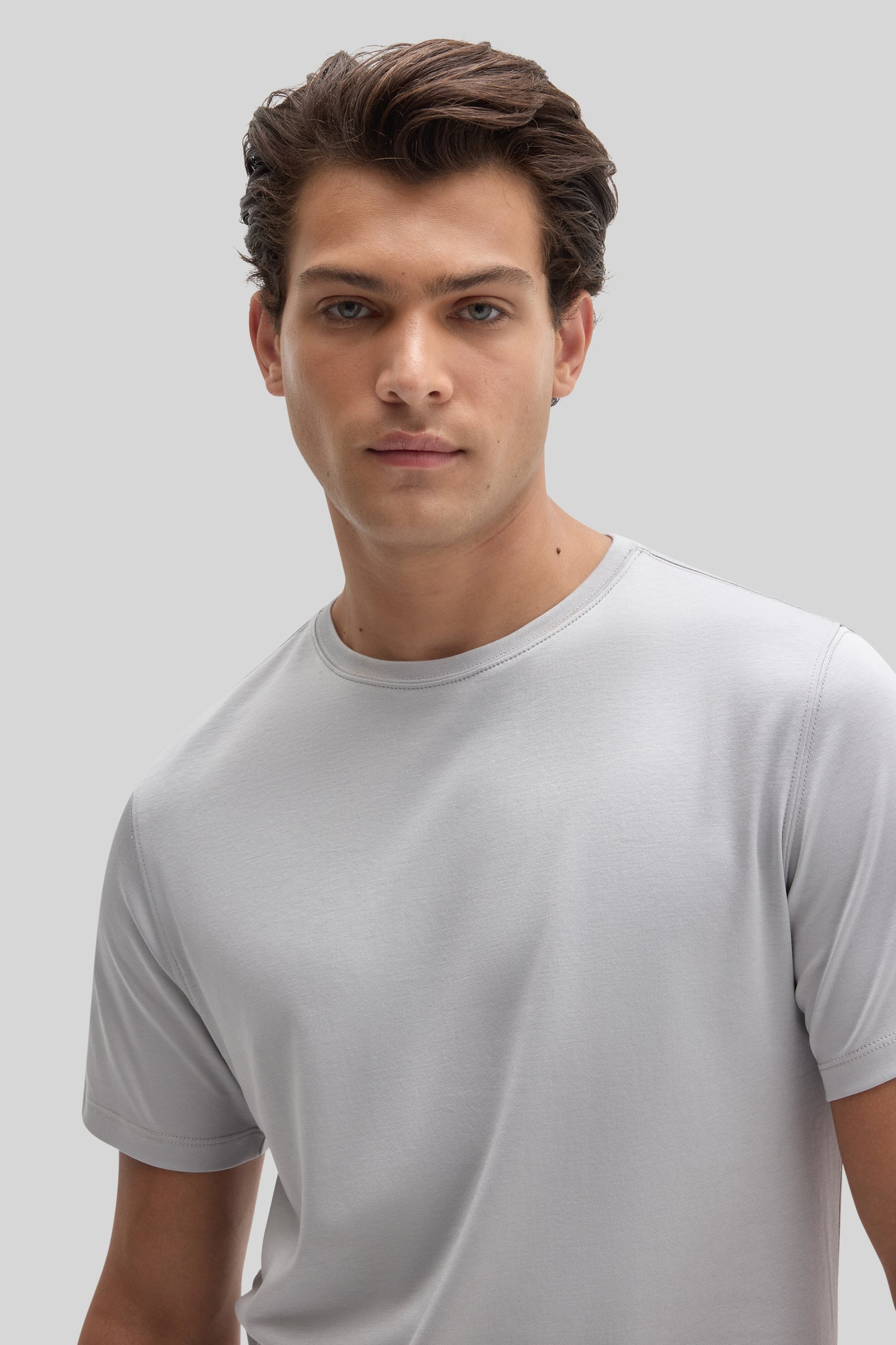 Man wearing a light gray crew neck t-shirt with short sleeves against a neutral background.