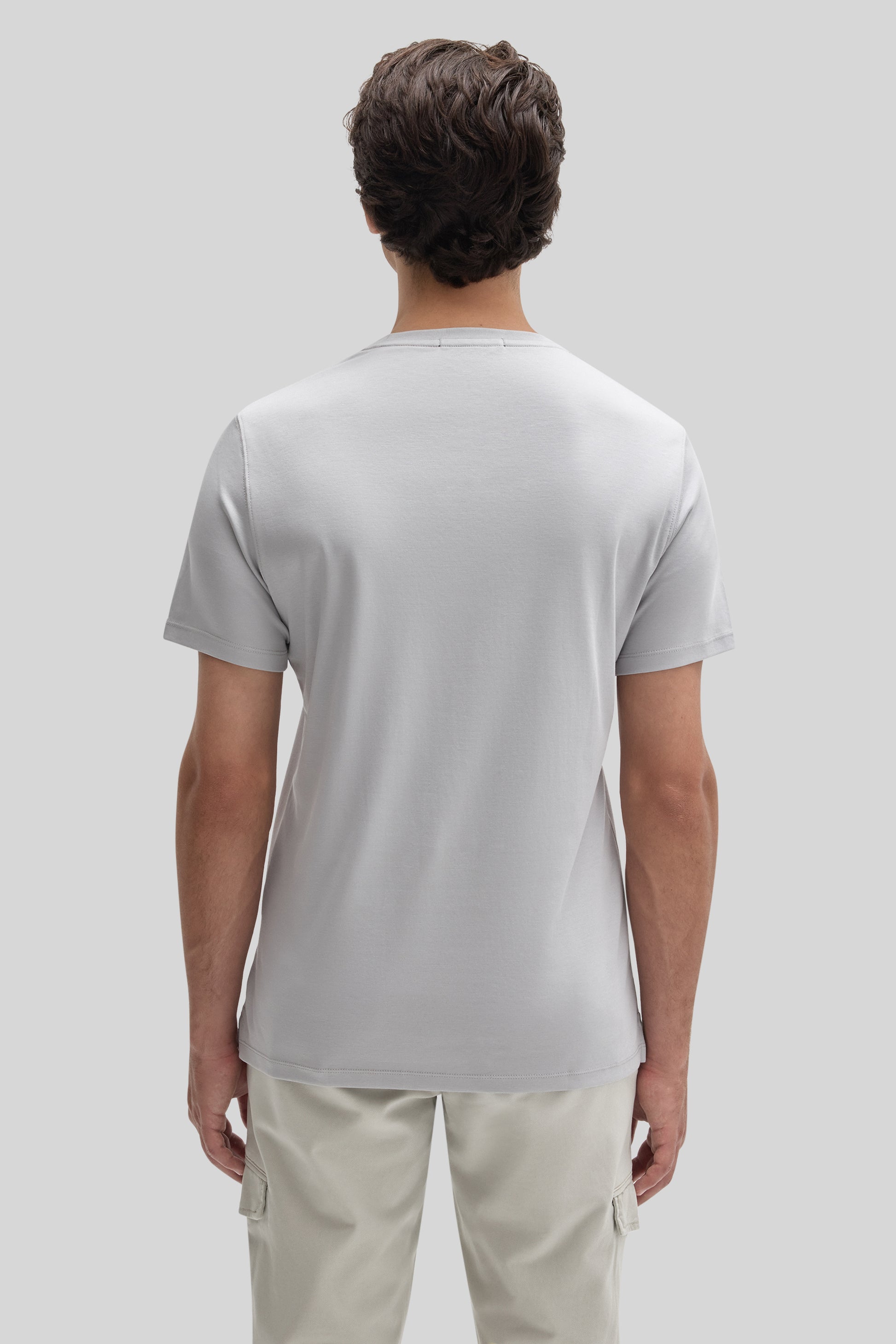 Man wearing light gray short-sleeve crew neck t-shirt with cream cargo pants, shown from back view.