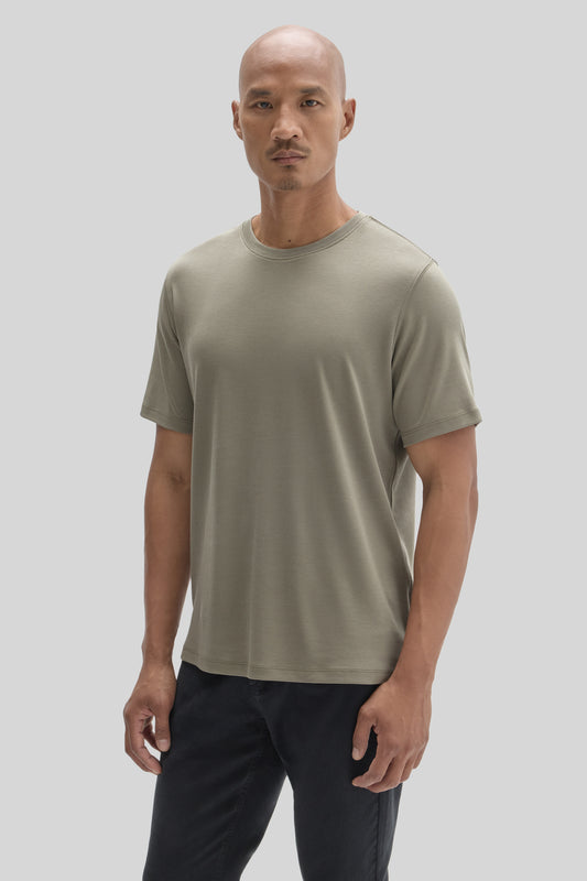 Man wearing a sage green crew neck t-shirt with short sleeves and black pants.