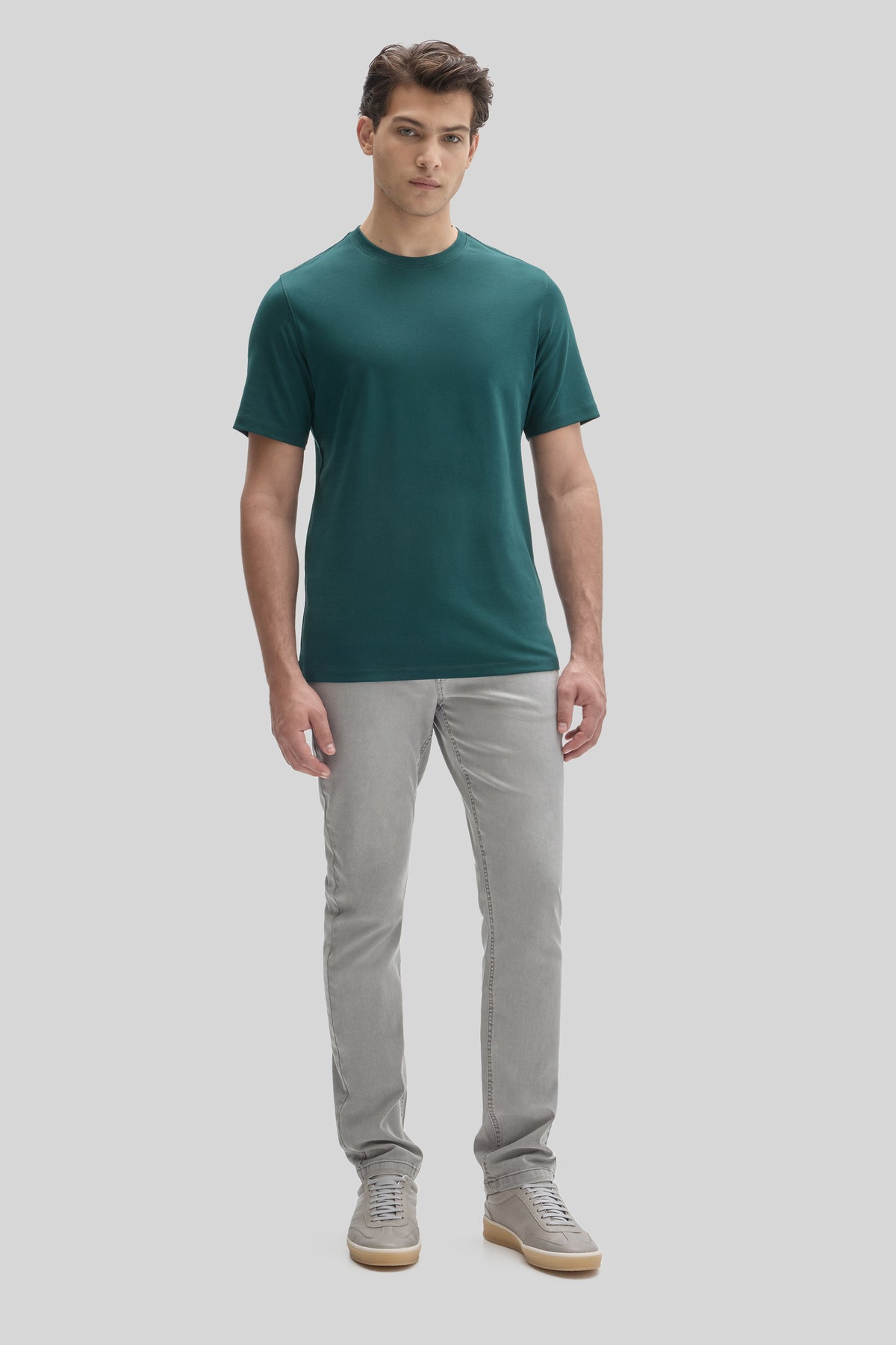 Man wearing teal crew neck t-shirt with short sleeves and gray jeans.