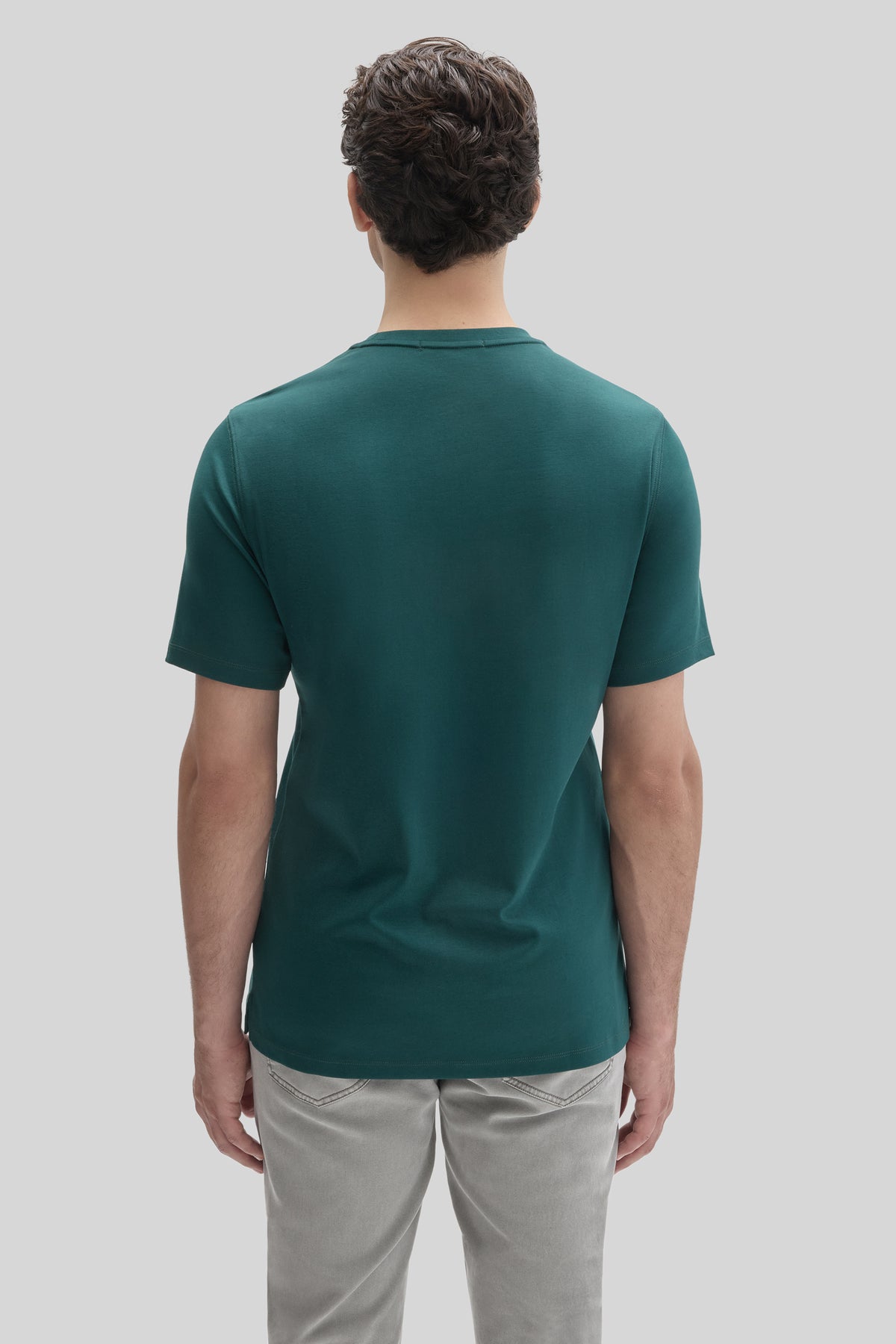 Man wearing a teal short-sleeved t-shirt and light gray pants, shown from behind.