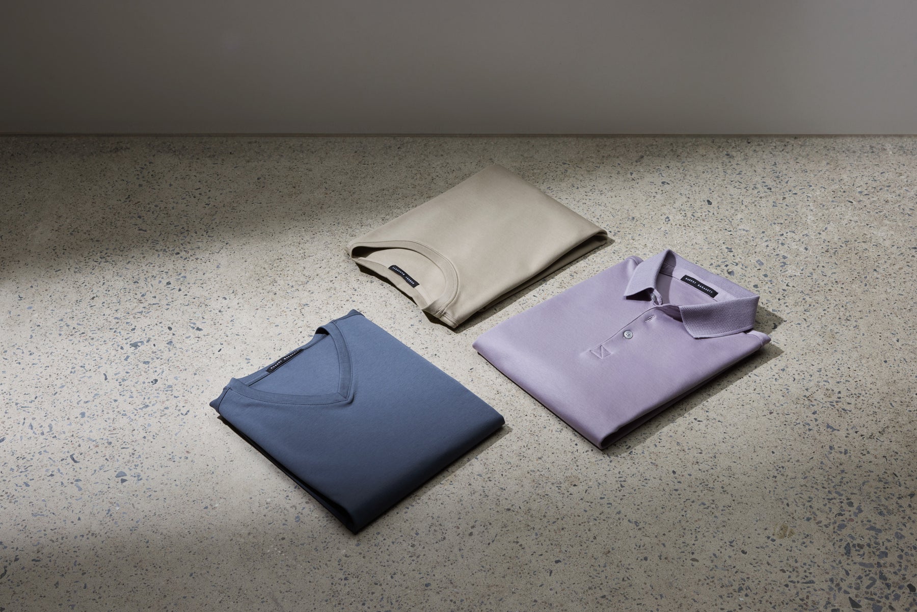 three shirts on a table, a polo shirt, v-neck t-shirt and round-neck t-shirt
