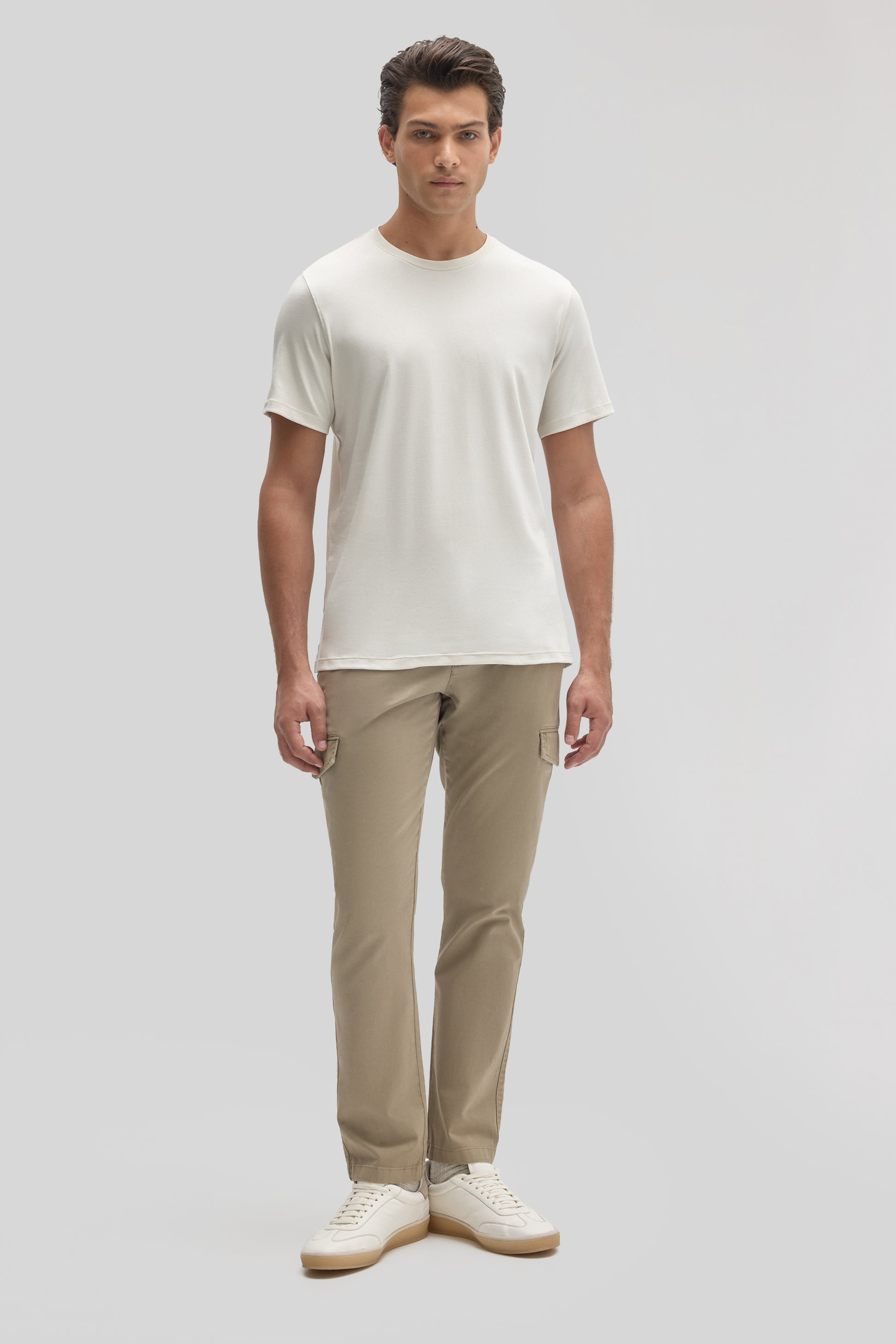 Man wearing cream short-sleeve crew neck t-shirt with beige cargo pants and white sneakers.