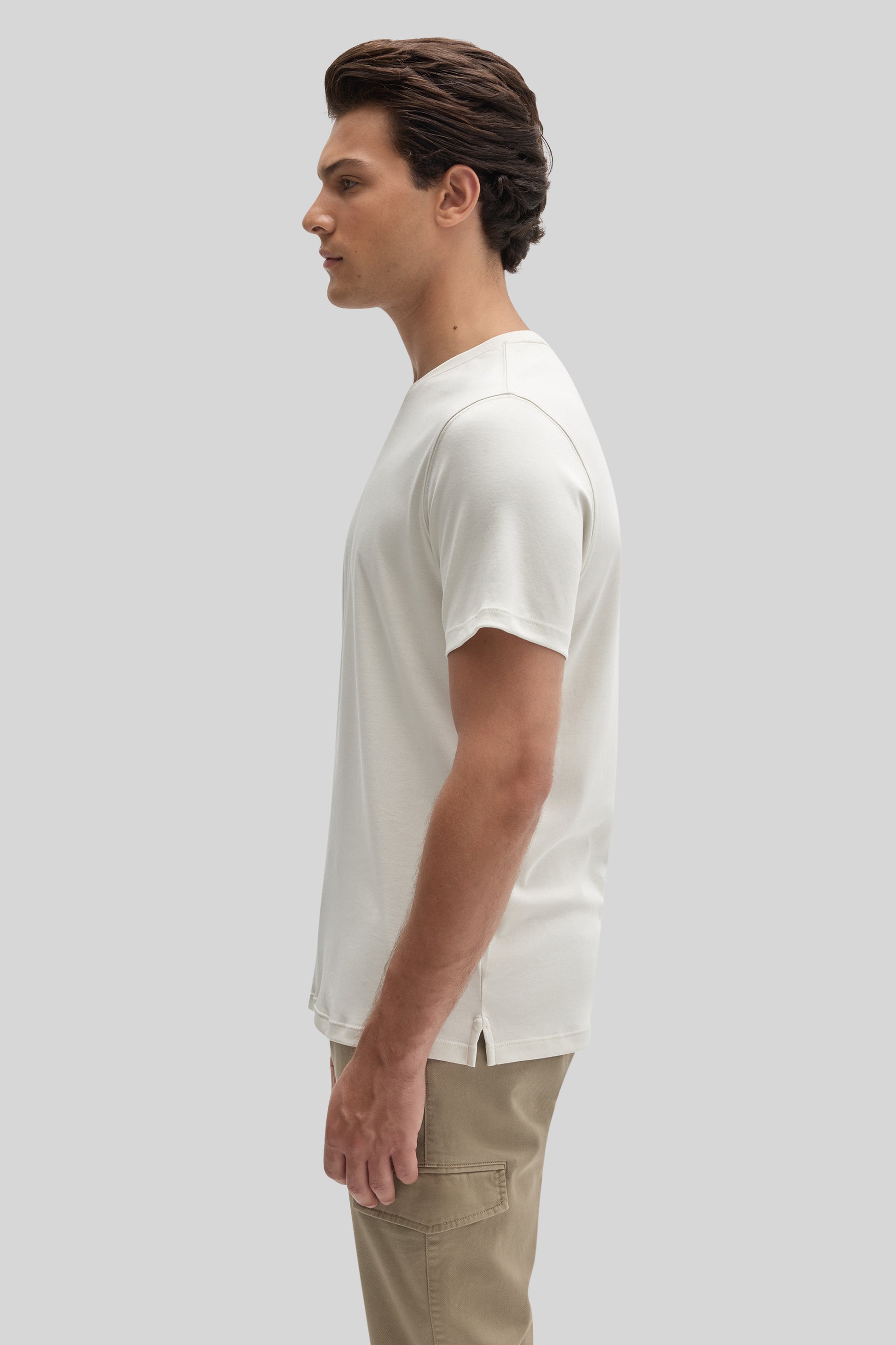 Man wearing white crew neck short-sleeve t-shirt with tan cargo pants, shown in profile view.