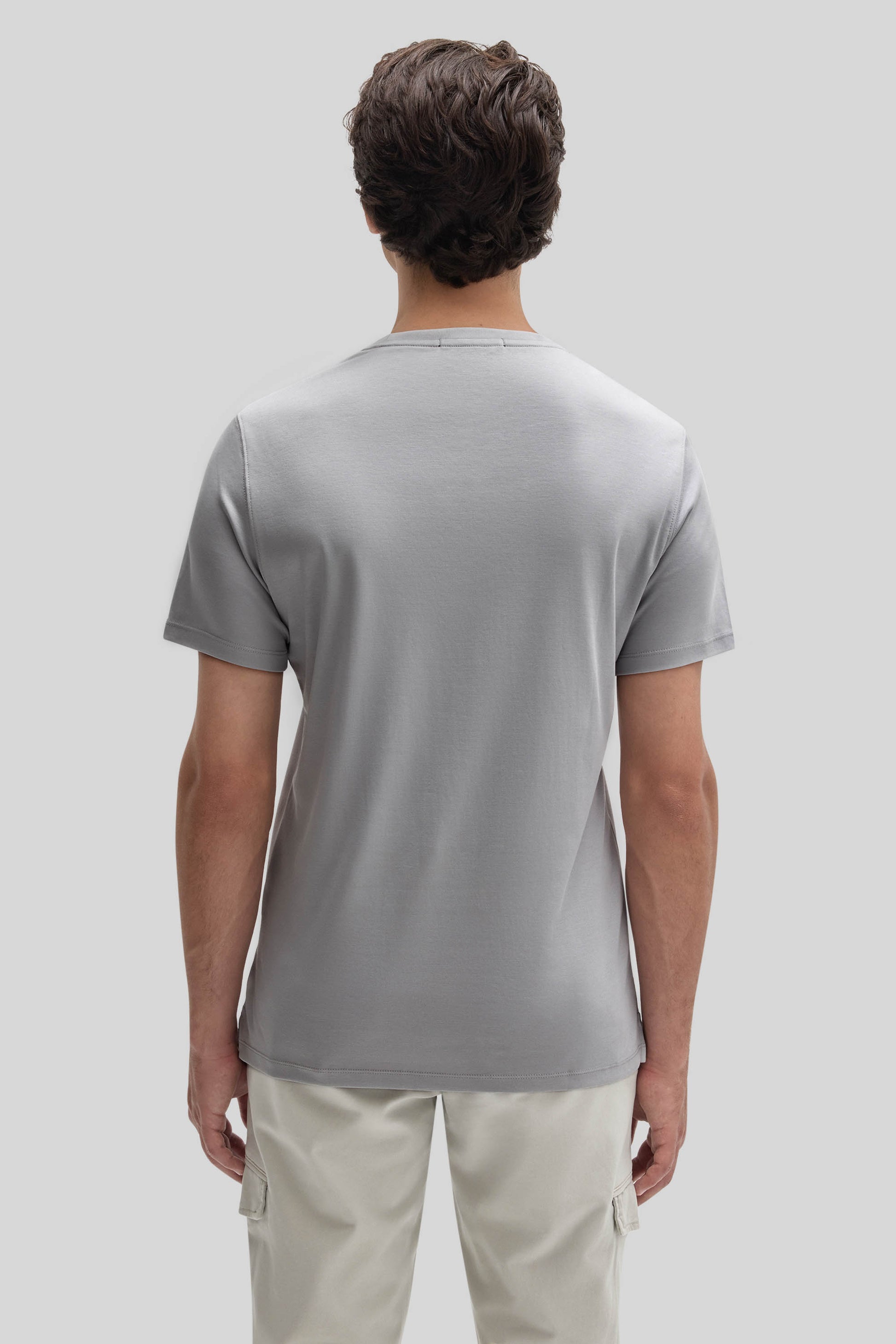 Man wearing light gray short-sleeve crew neck t-shirt and cream cargo pants, shown from back view.