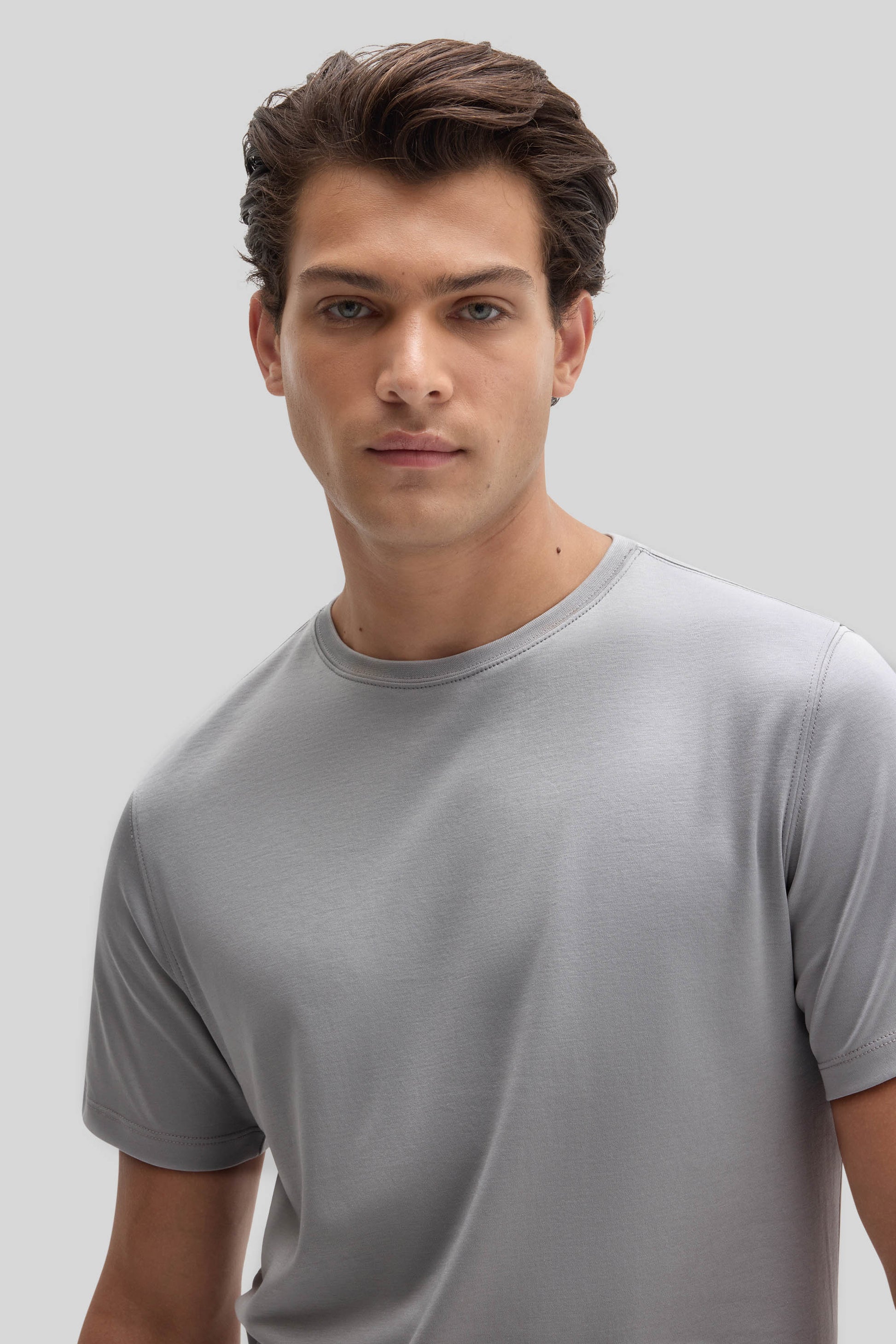 Man wearing light gray crew-neck short-sleeve t-shirt against neutral background.