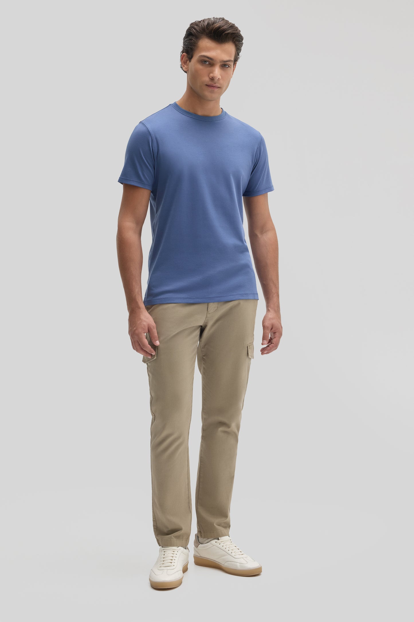 Man wearing blue crew neck t-shirt with beige cargo pants and white sneakers.