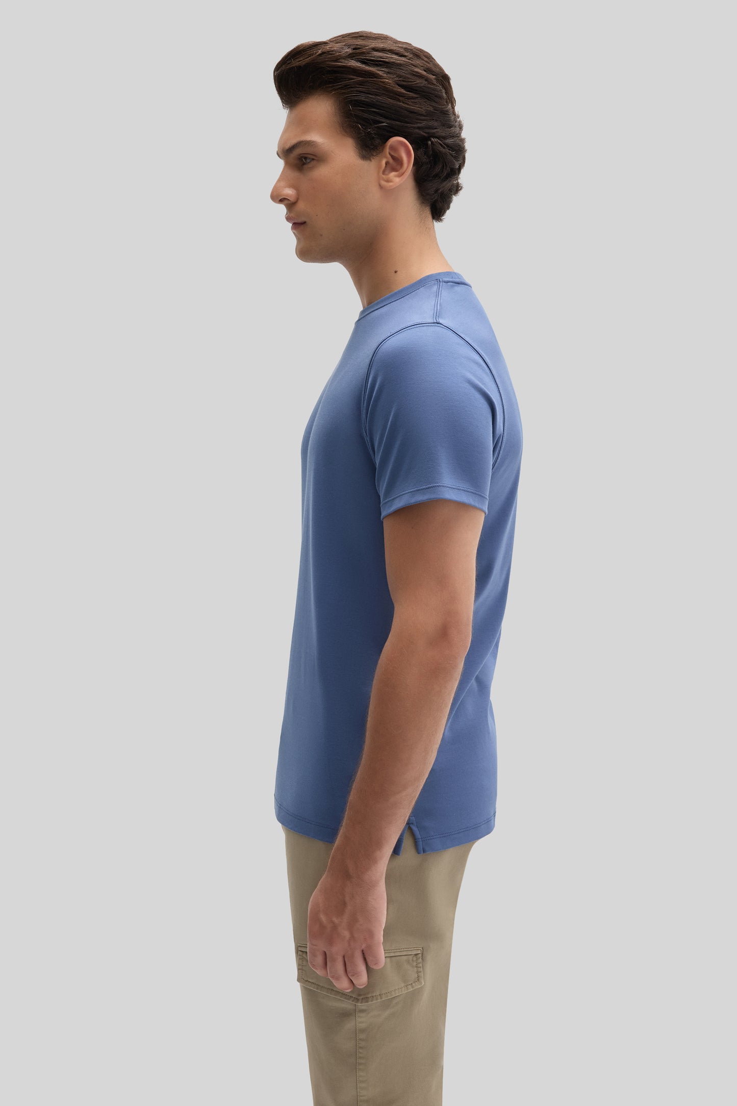 Man wearing a blue short-sleeve crew neck t-shirt paired with beige cargo pants, shown in profile view.