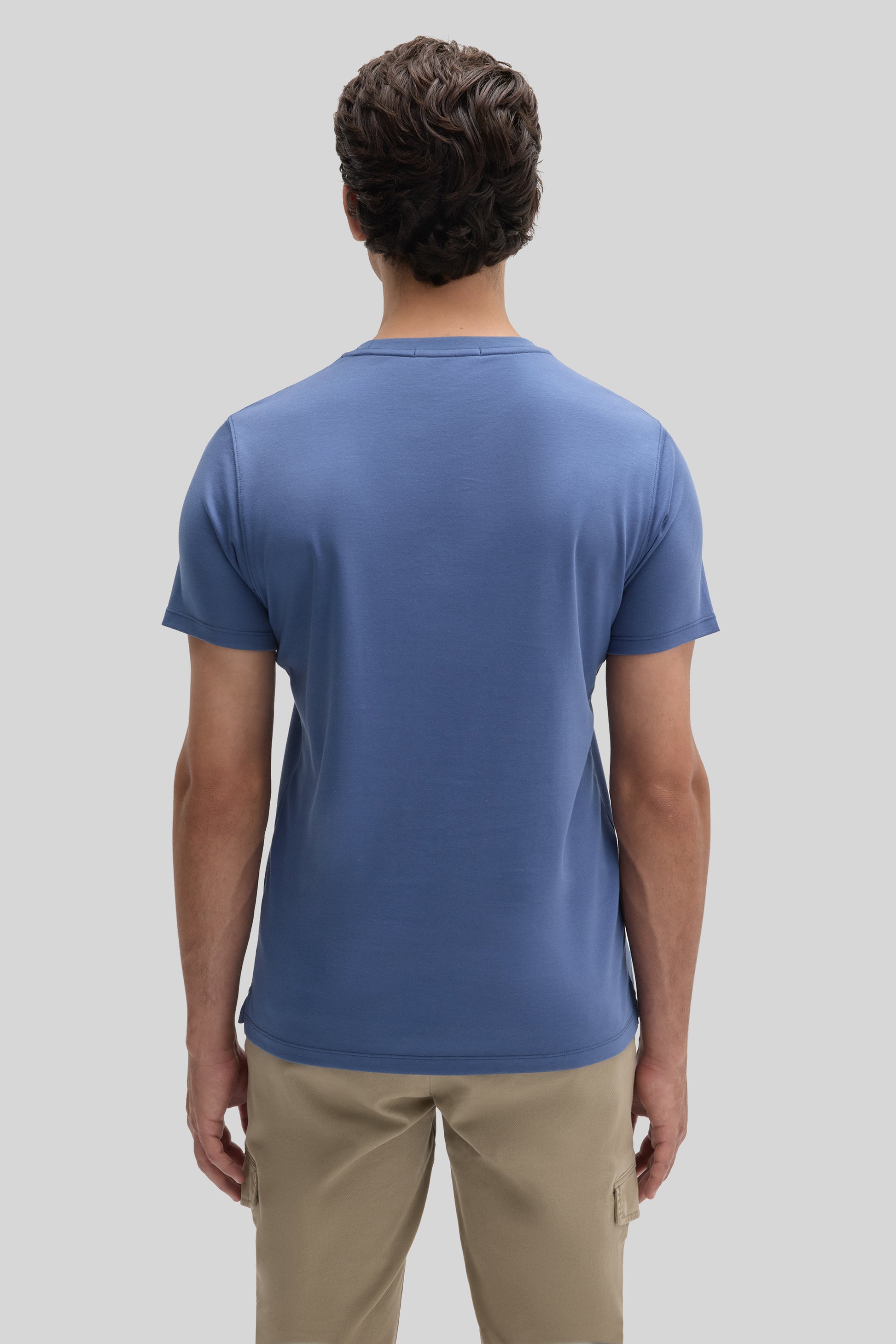 Man wearing blue short-sleeve t-shirt and beige cargo pants, shown from back view.