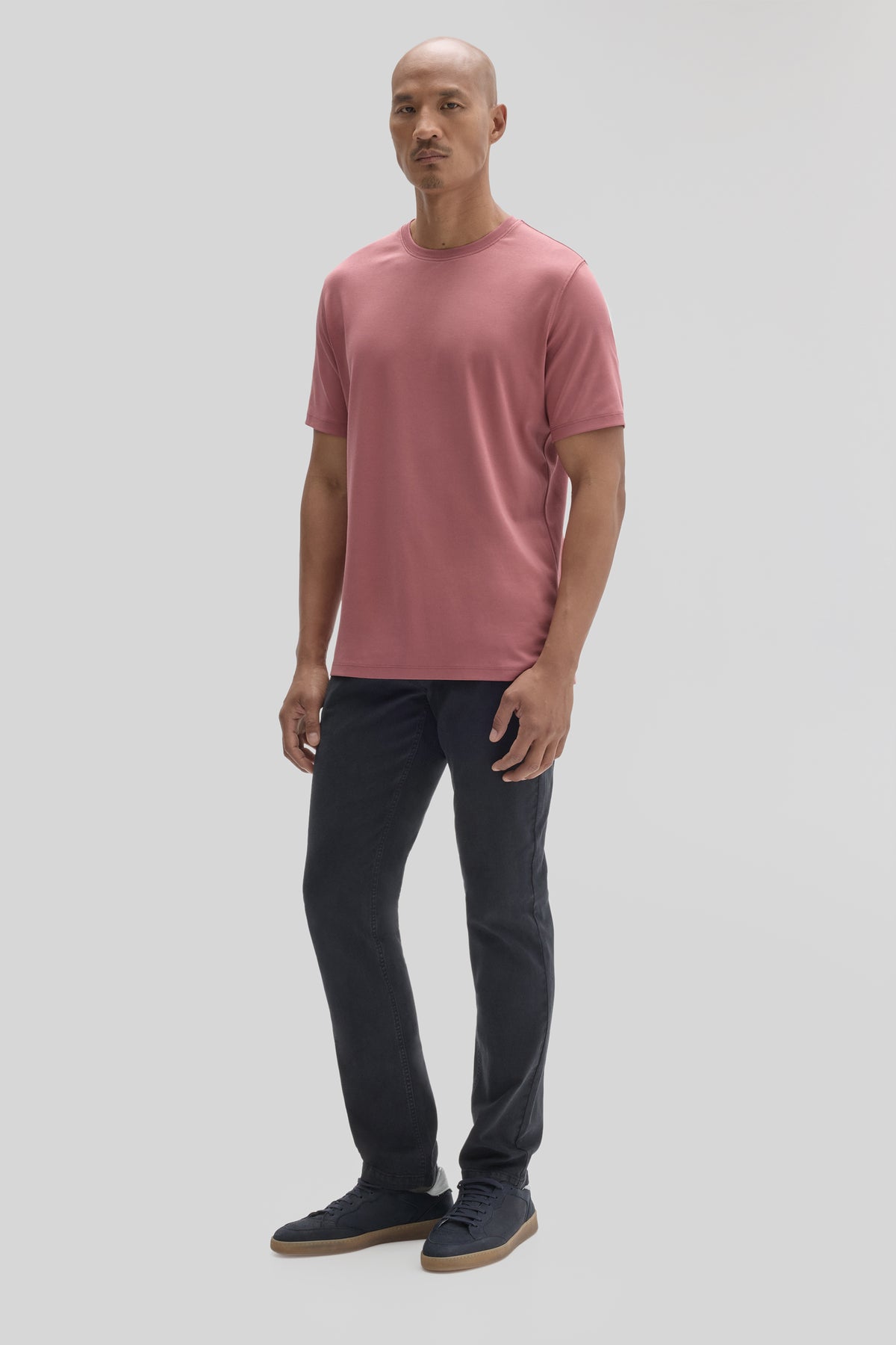 Man wearing mauve short-sleeve t-shirt with crew neckline and dark jeans.