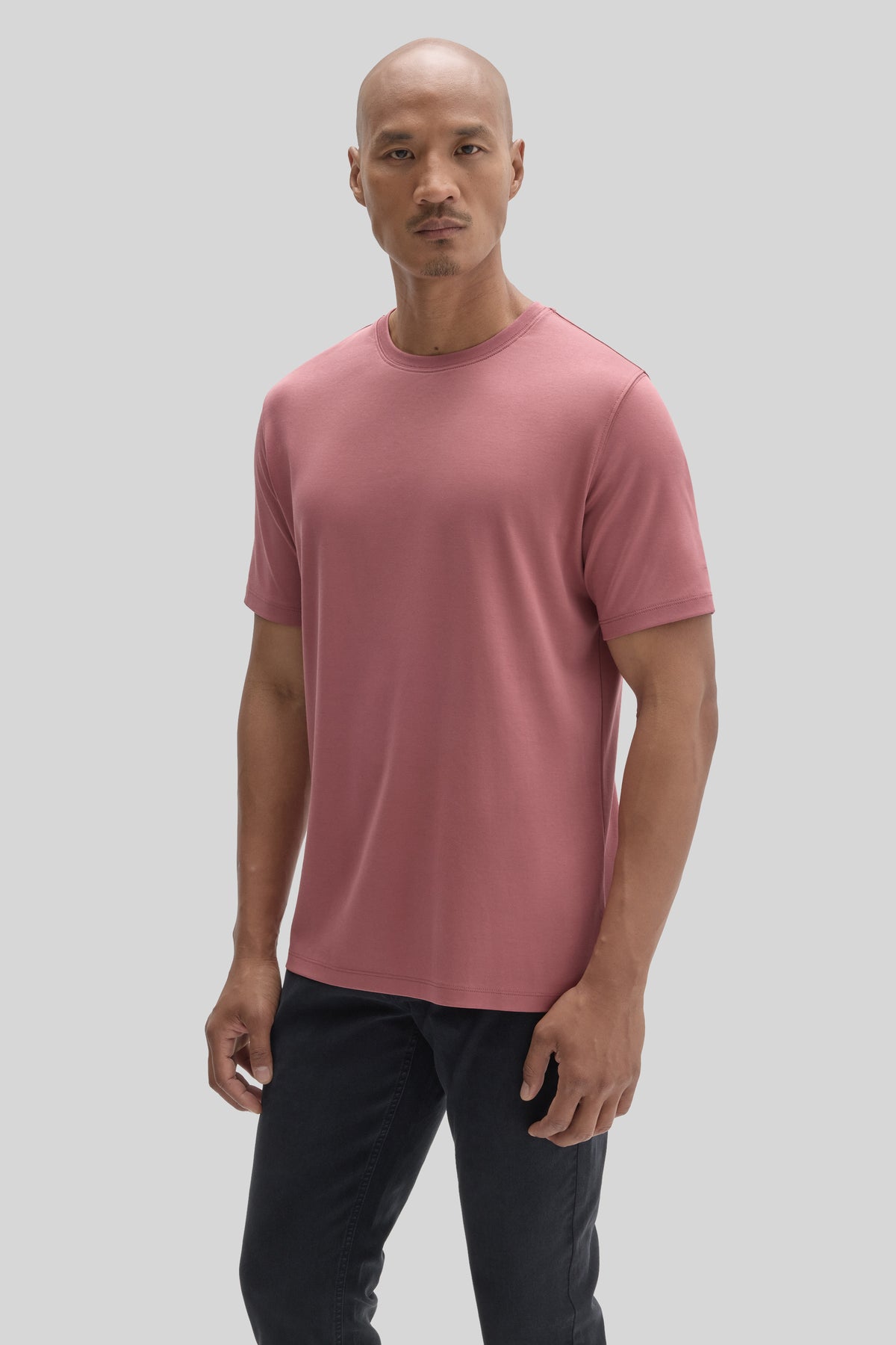 Man wearing a mauve pink short-sleeve crew neck t-shirt with black jeans.