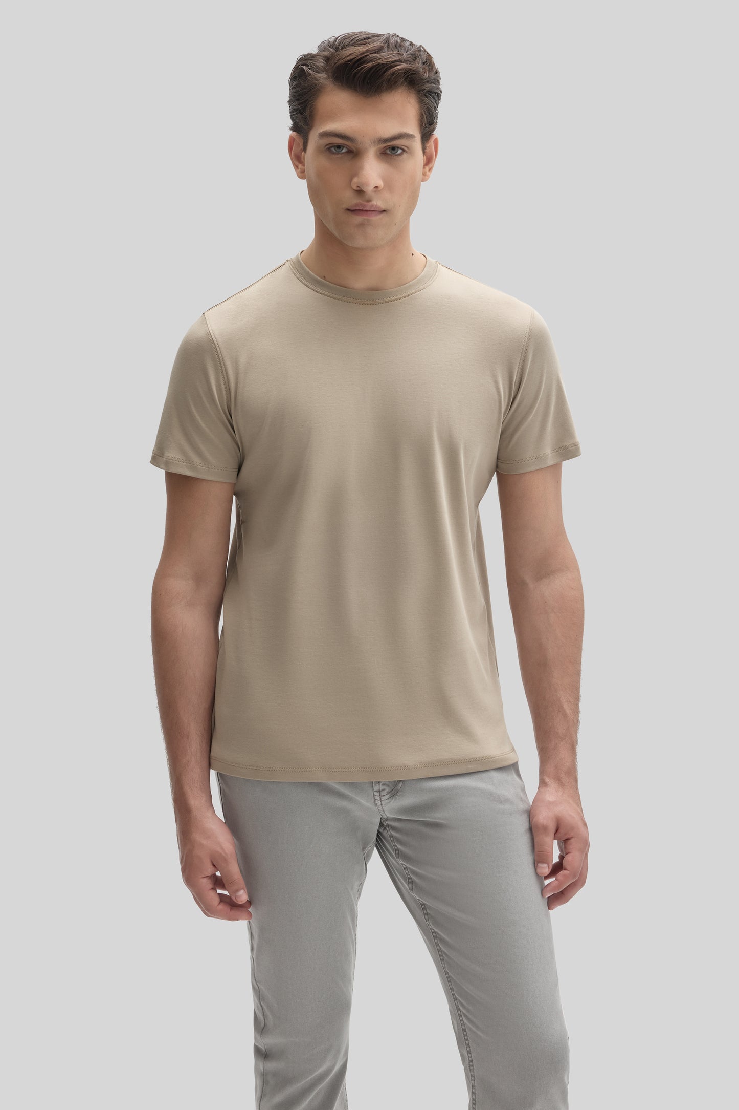 Man wearing a beige crew-neck short-sleeve t-shirt with gray pants.