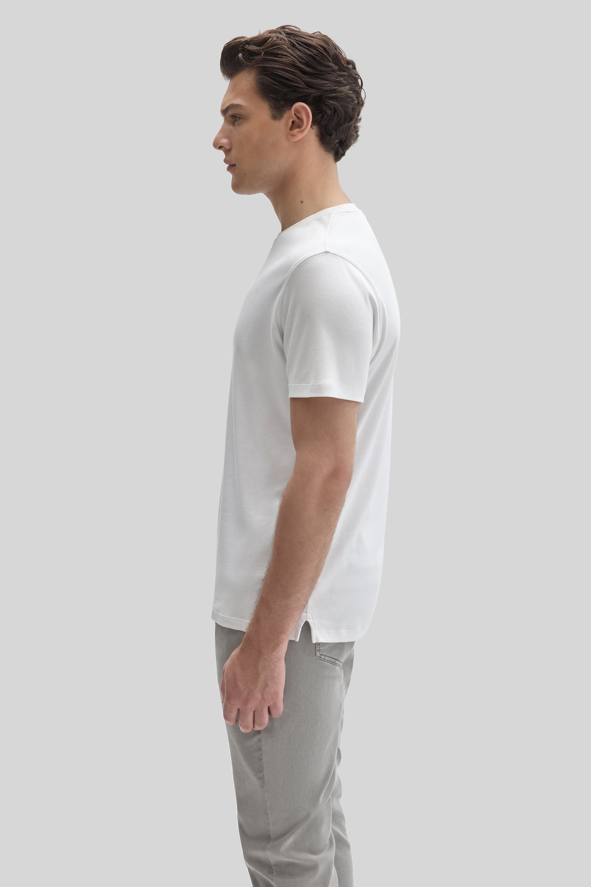 Man wearing white short-sleeve t-shirt and light gray pants, shown in profile view.
