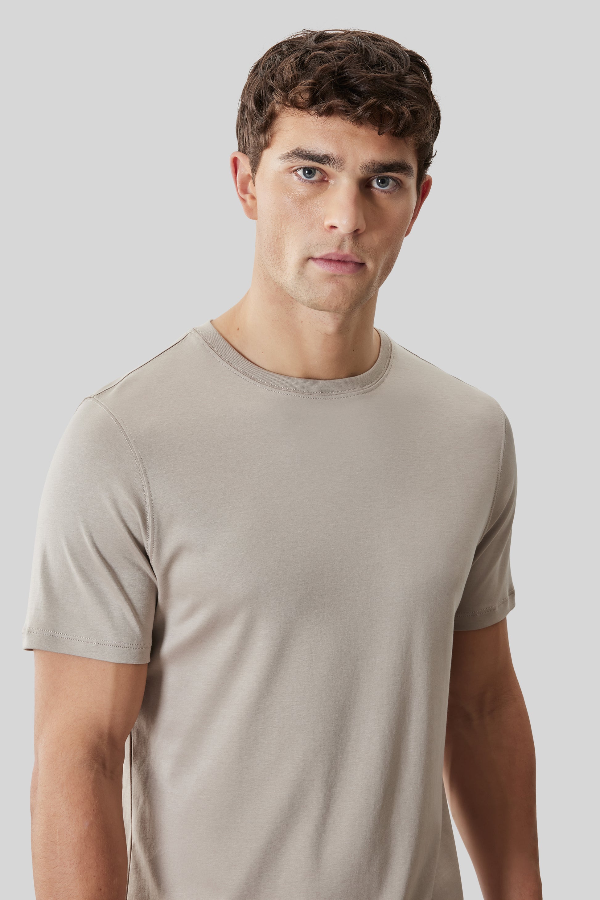 Beige crew neck t-shirt with short sleeves on male model against neutral background.