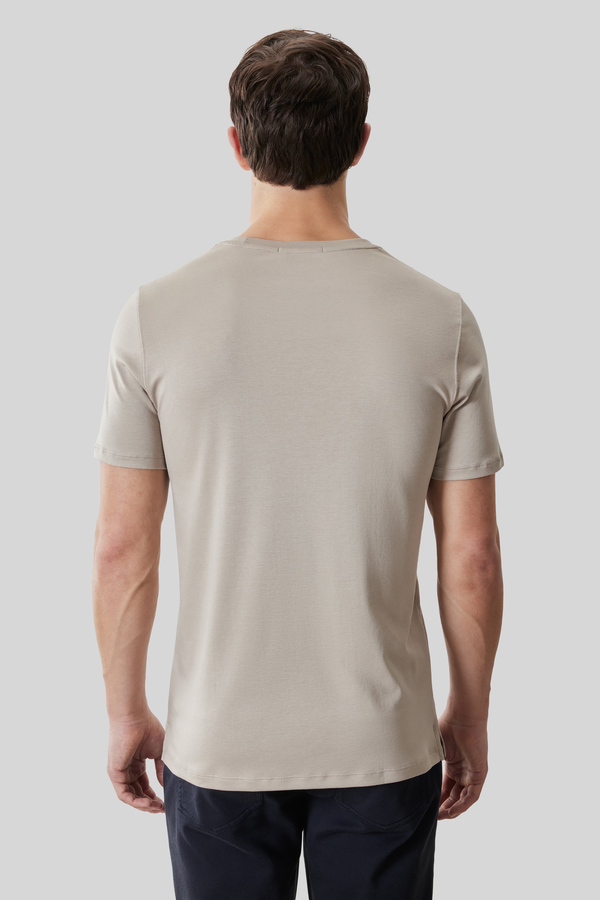 Beige crew neck t-shirt with short sleeves, shown from back view on a model wearing dark pants.