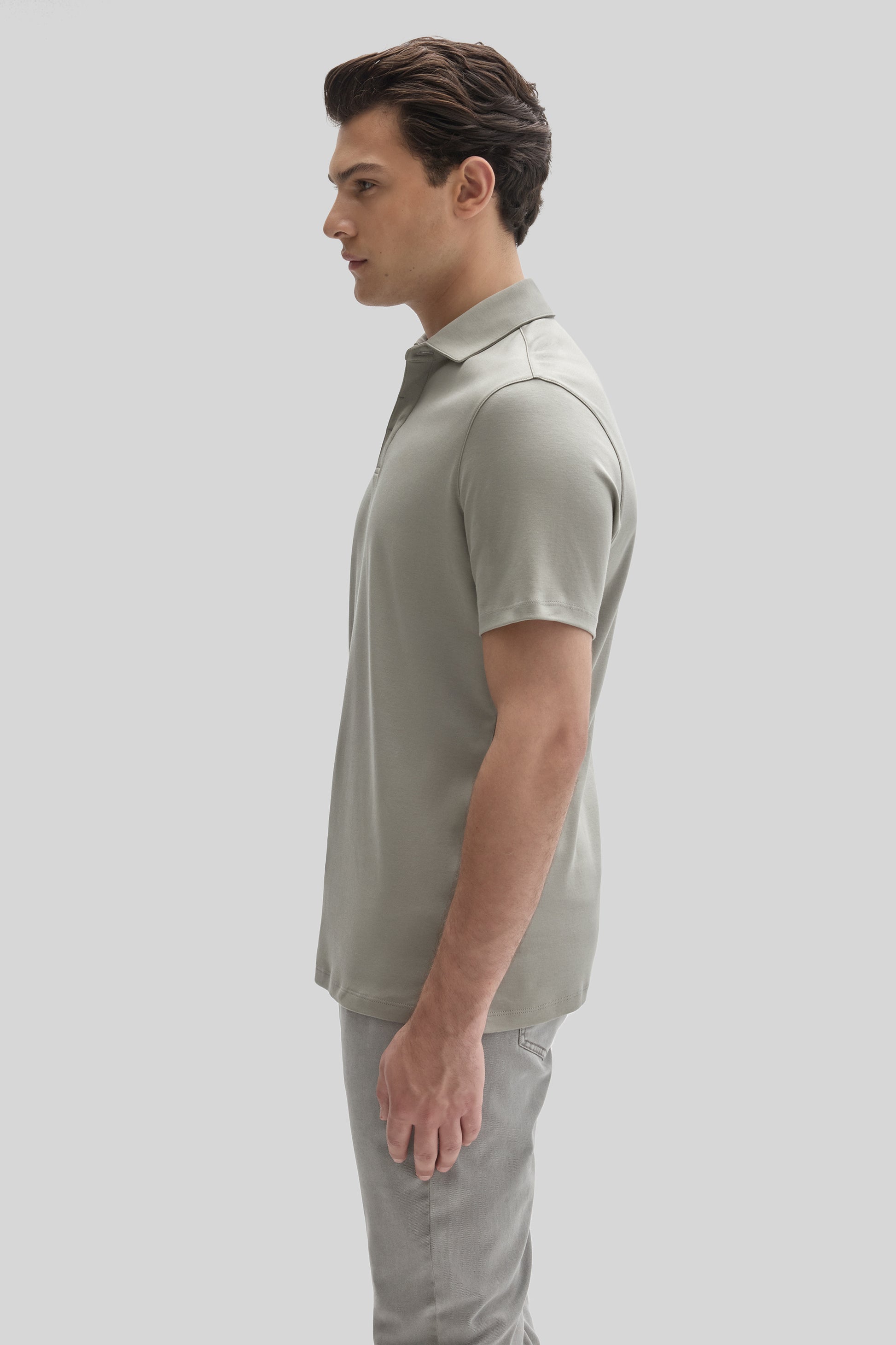 Man wearing light gray short-sleeve polo shirt with collared neckline, paired with gray trousers.
