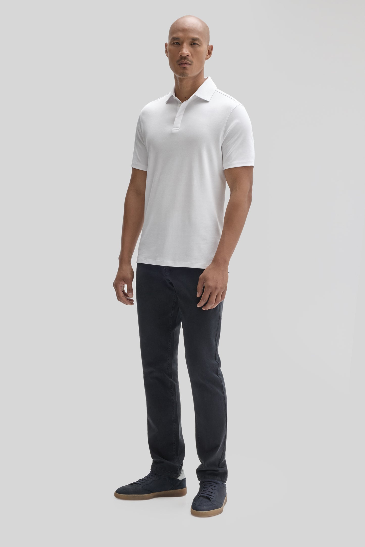 Man wearing white short-sleeve polo shirt with covered placket and dark jeans.